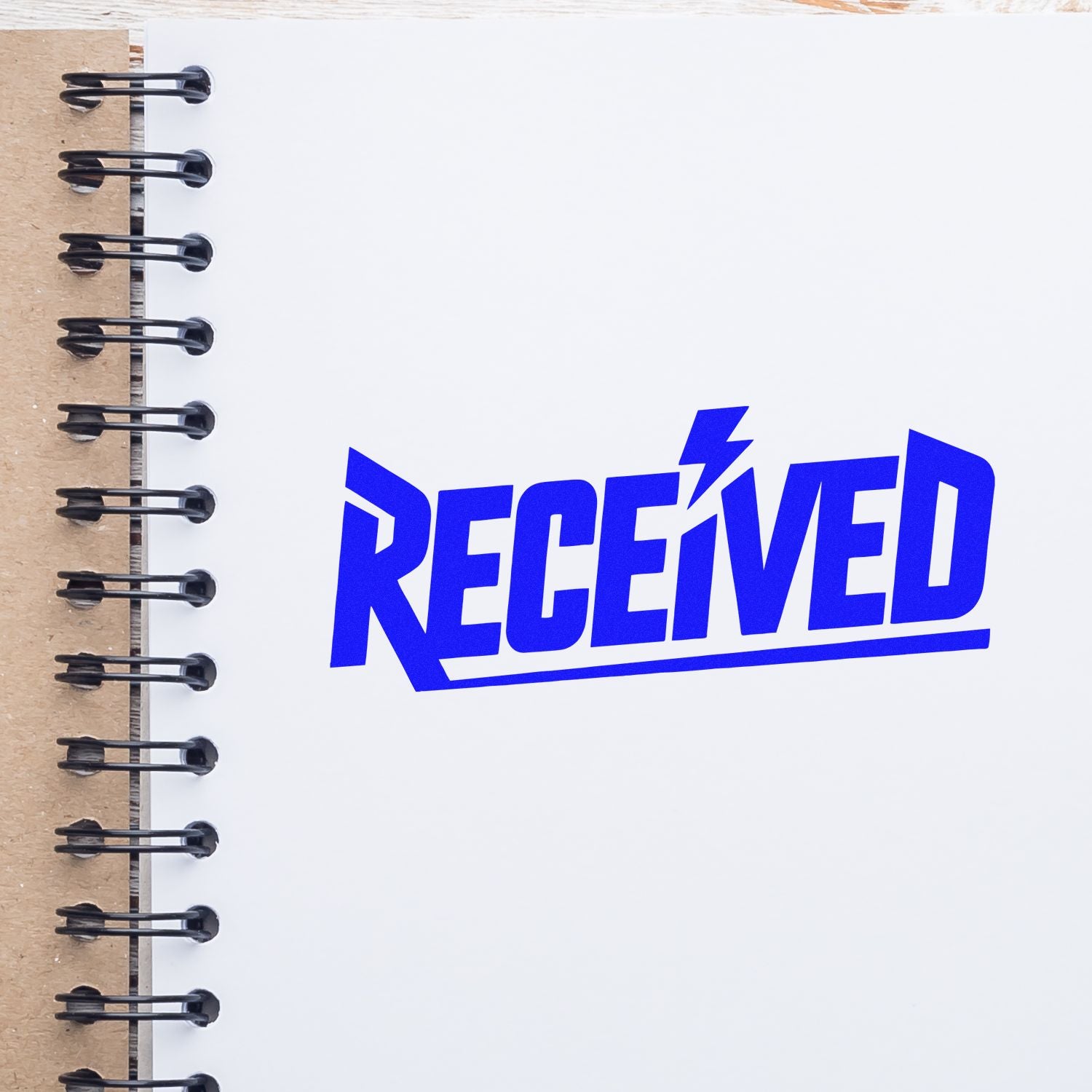 Blue RECEIVED stamp and seal graphic on a white spiral notebook with kraft paper binding.