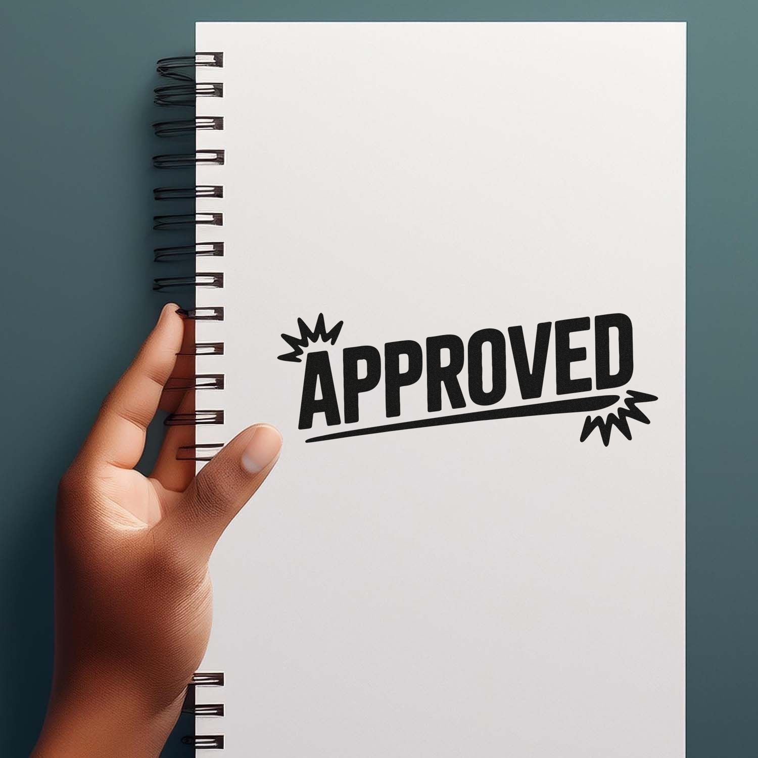 Black APPROVED stamp seal on a white spiral notebook held by hand against a teal background.
