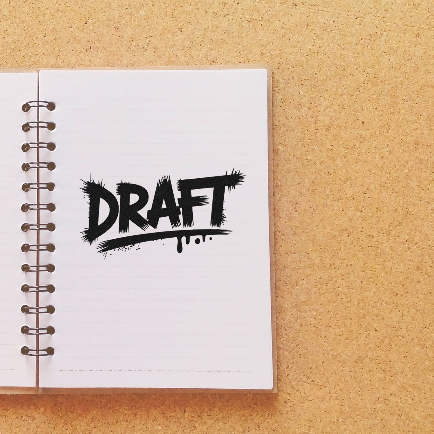Black DRAFT stamp/seal on a white spiral notebook page, set against a tan cork background.