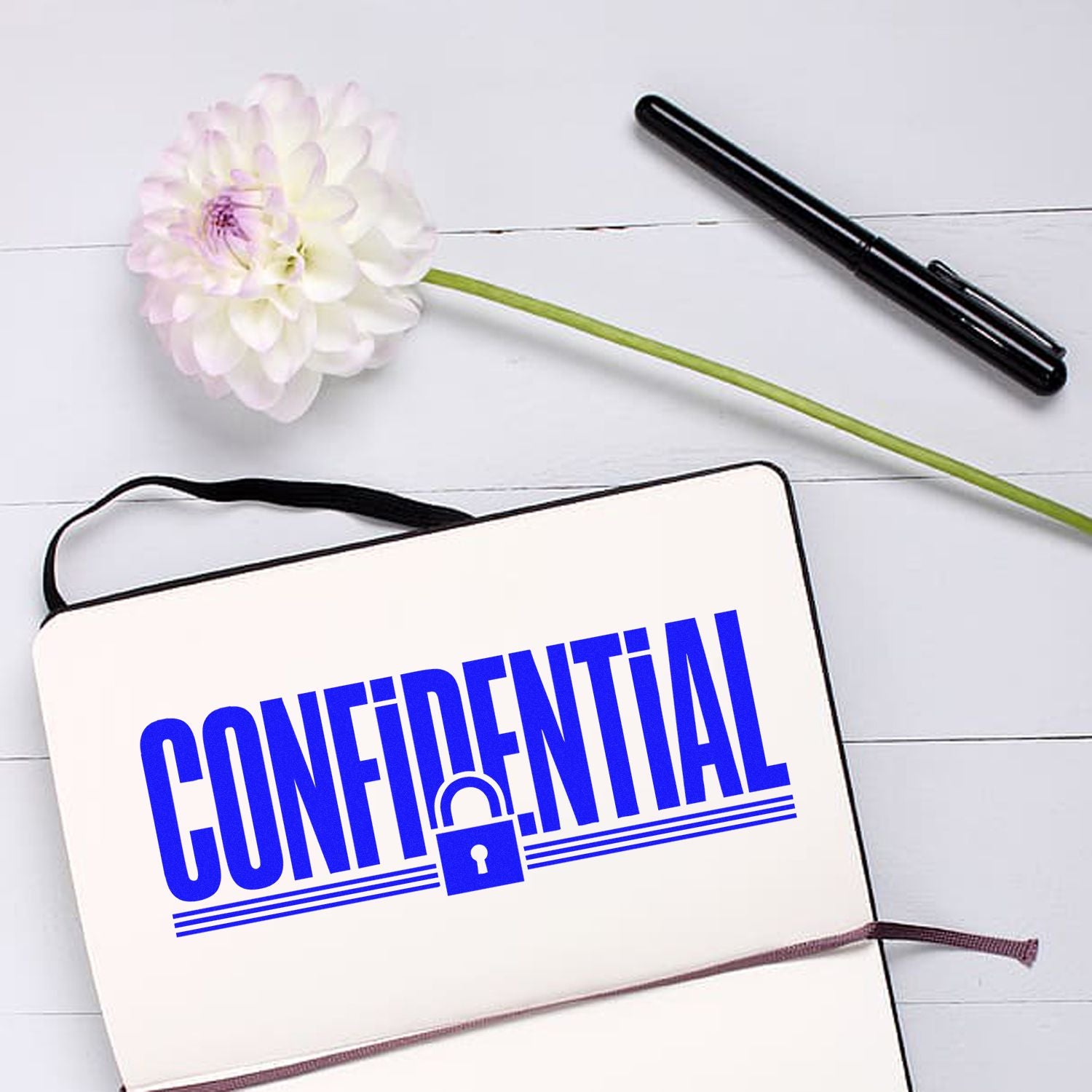Blue CONFIDENTIAL stamp seal with padlock on white notebook, beside black pen and white flower
