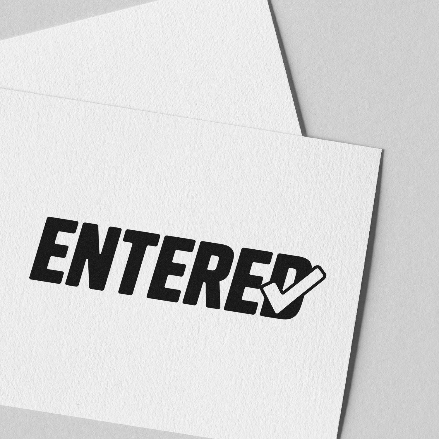 Black ENTERED stamp with checkmark on white textured paper and envelope, showing seal and stamp product design.