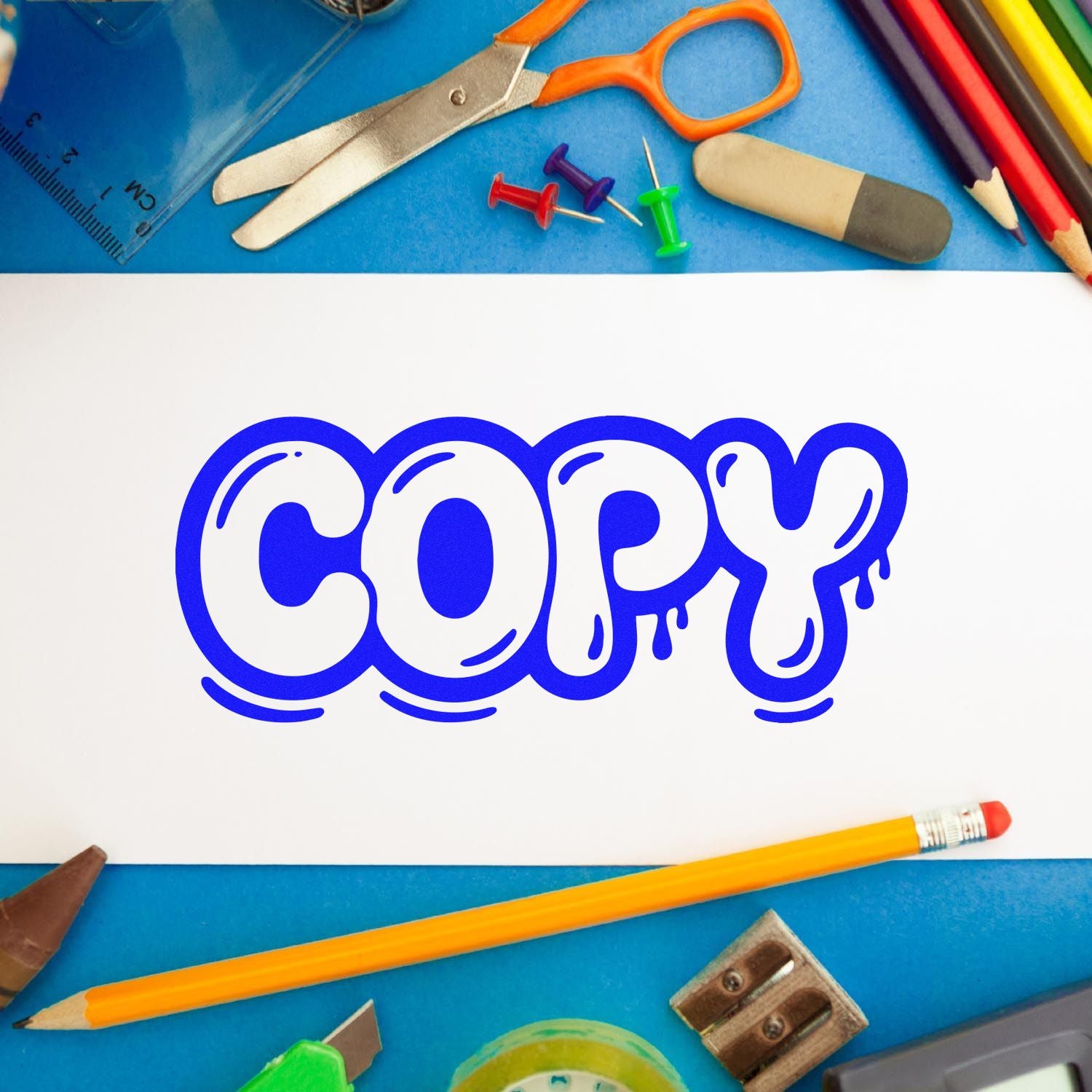 Blue COPY stamp-and-seal design on white paper, surrounded by stationery, pencils, scissors, and push pins.