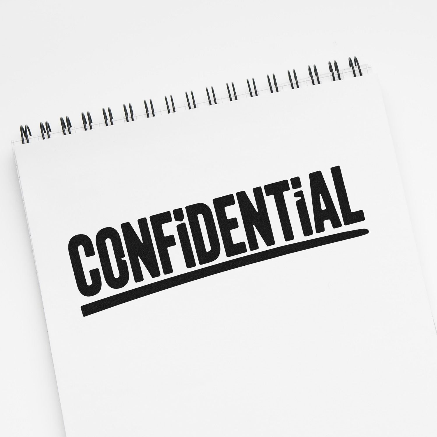 Black CONFIDENTIAL stamp on a white spiral notebook, bold underlined text for secure document sealing.