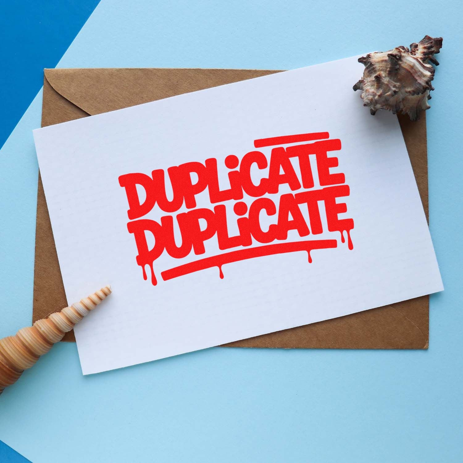 Red DUPLICATE stamp on white card over a brown envelope, with seashell seal accents on a light blue background.