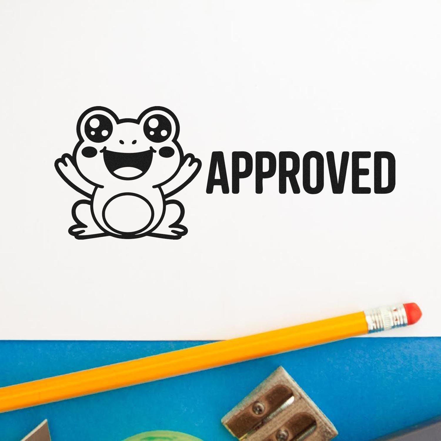 Black frog APPROVED stamp seal on white paper, with pencil on a blue desk