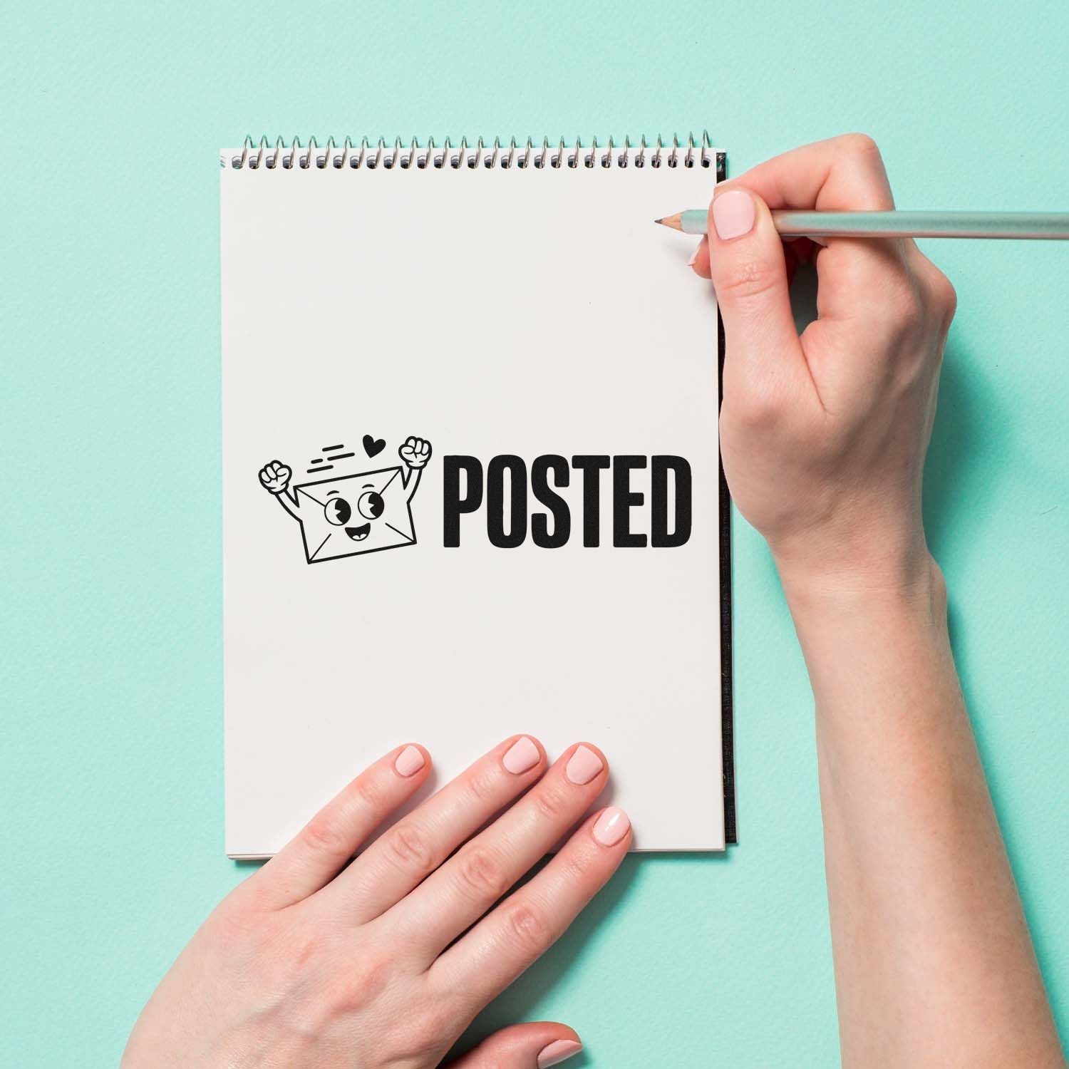 White notebook page with black POSTED stamp and smiling envelope seal, on mint background with hand holding a pencil.