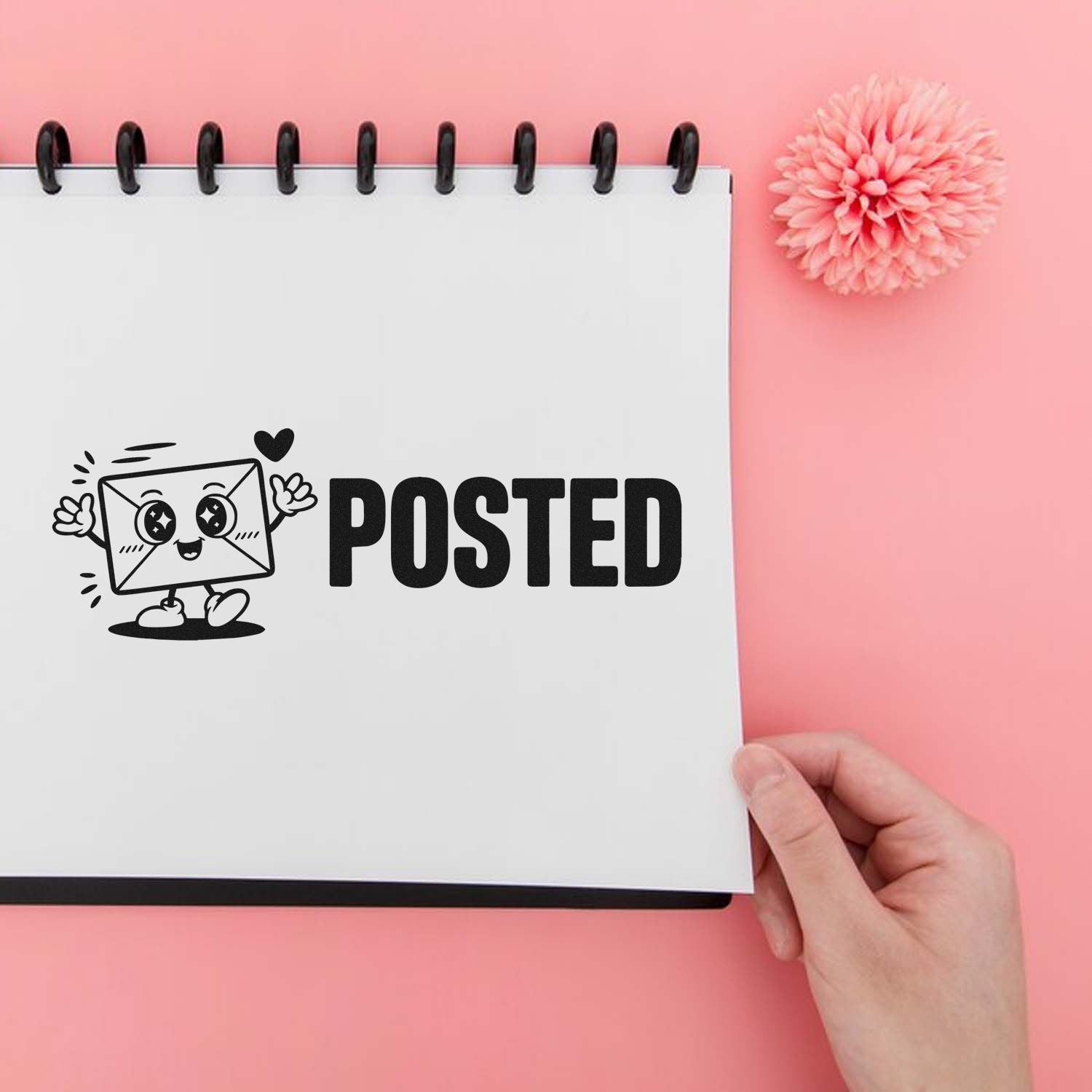 Black POSTED stamp with cute envelope seal on white notebook, pink background, hand holding page, pink flower.