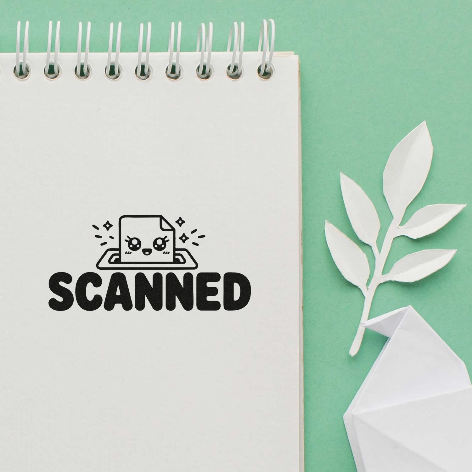 White spiral notebook with black SCANNED stamp, cute scan icon, on mint green background with white paper leaf and origami accent.