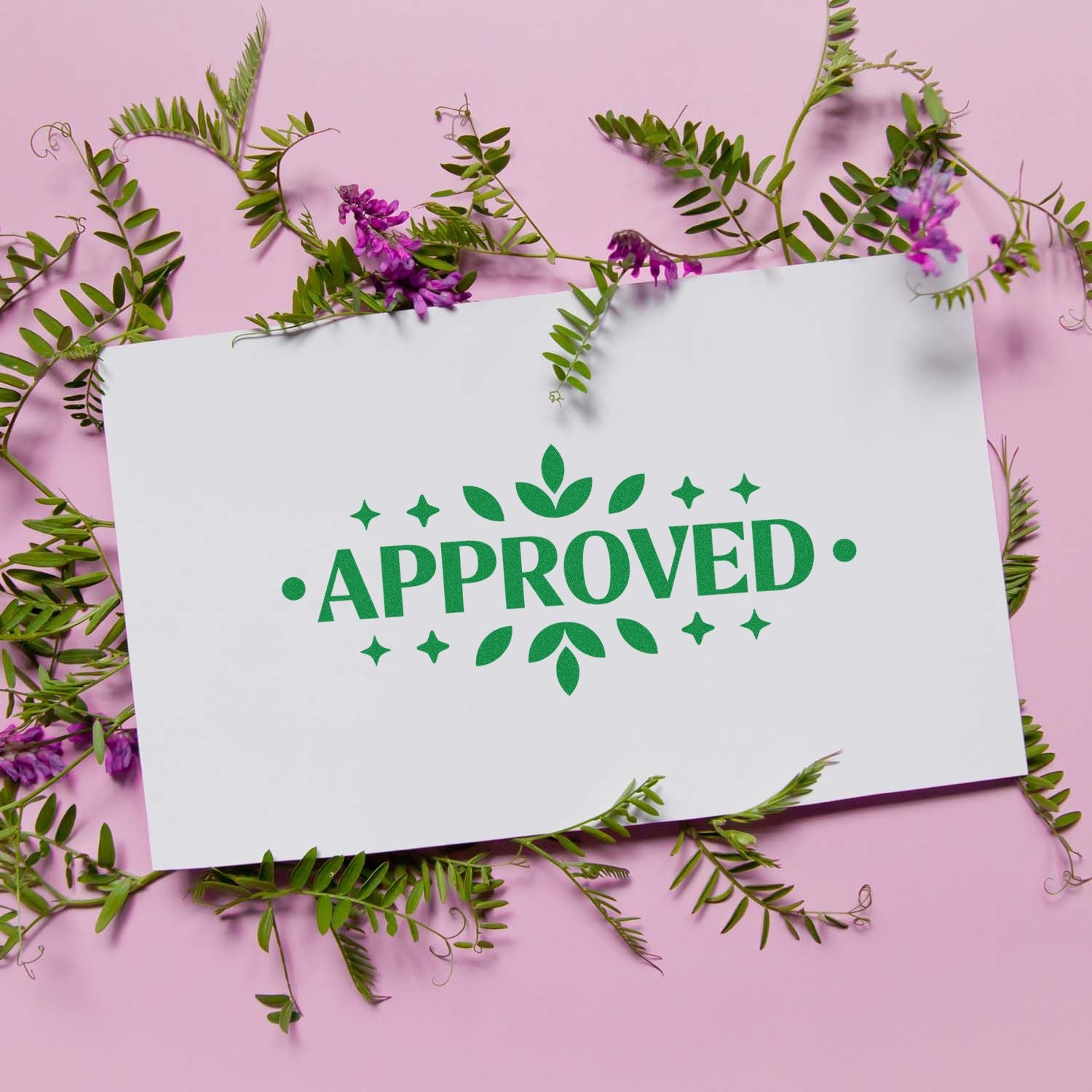Green APPROVED stamp and seal on white card, framed by green vines and purple flowers on a pink background.