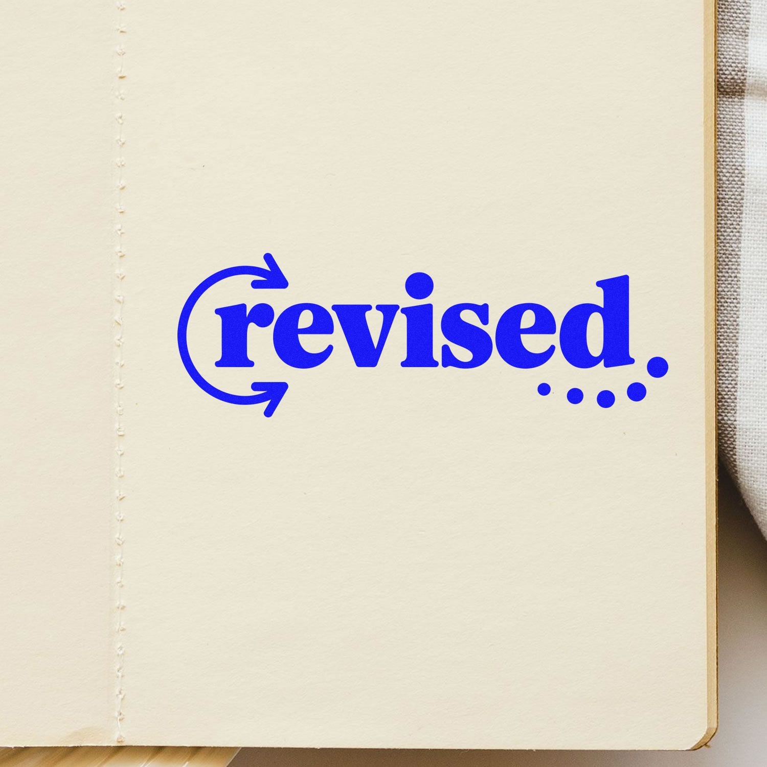Blue revised stamp and seal on cream notebook page with circular arrows and dotted underline.