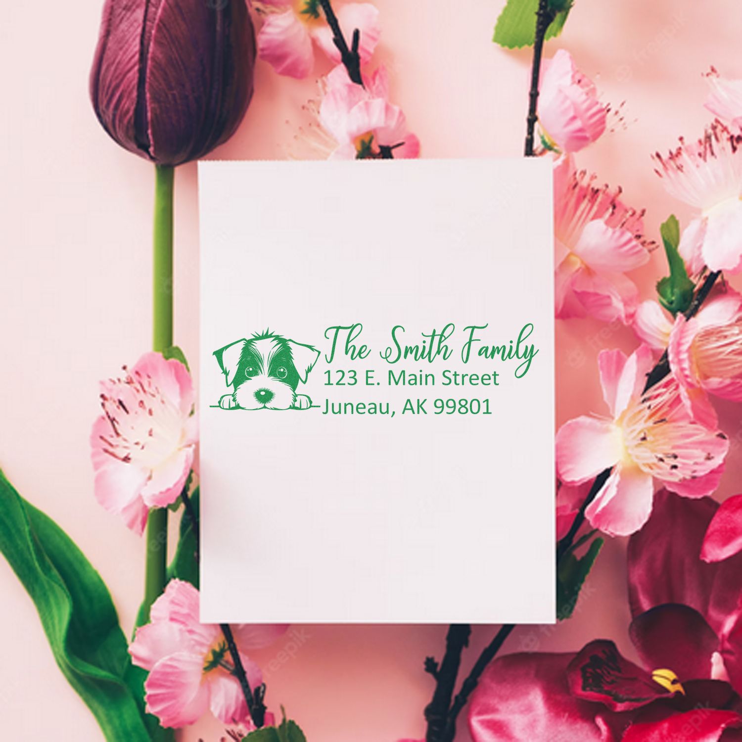 Green custom return address stamp with dog logo on white card, set against pink floral background.