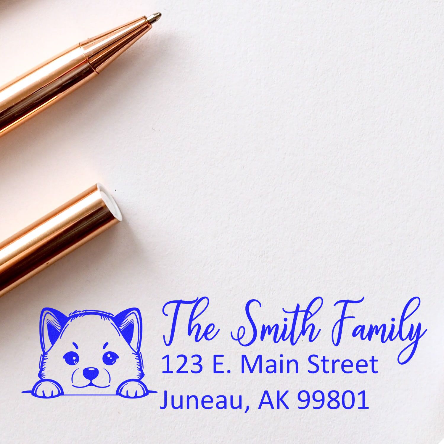 Gold stamp and seal tools beside a blue custom address stamp with dog logo, The Smith Family, Juneau, AK 99801.