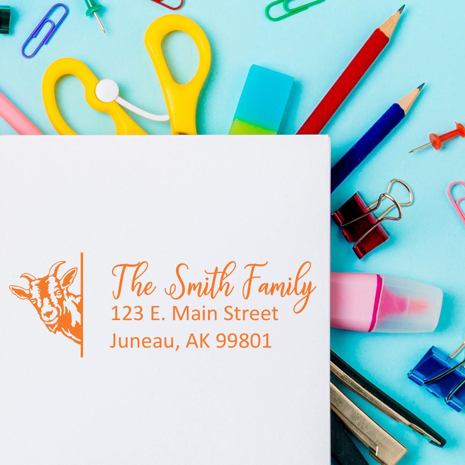 Orange personalized stamp and seal on white paper, with goat logo and Smith Family address on a bright blue stationery background.