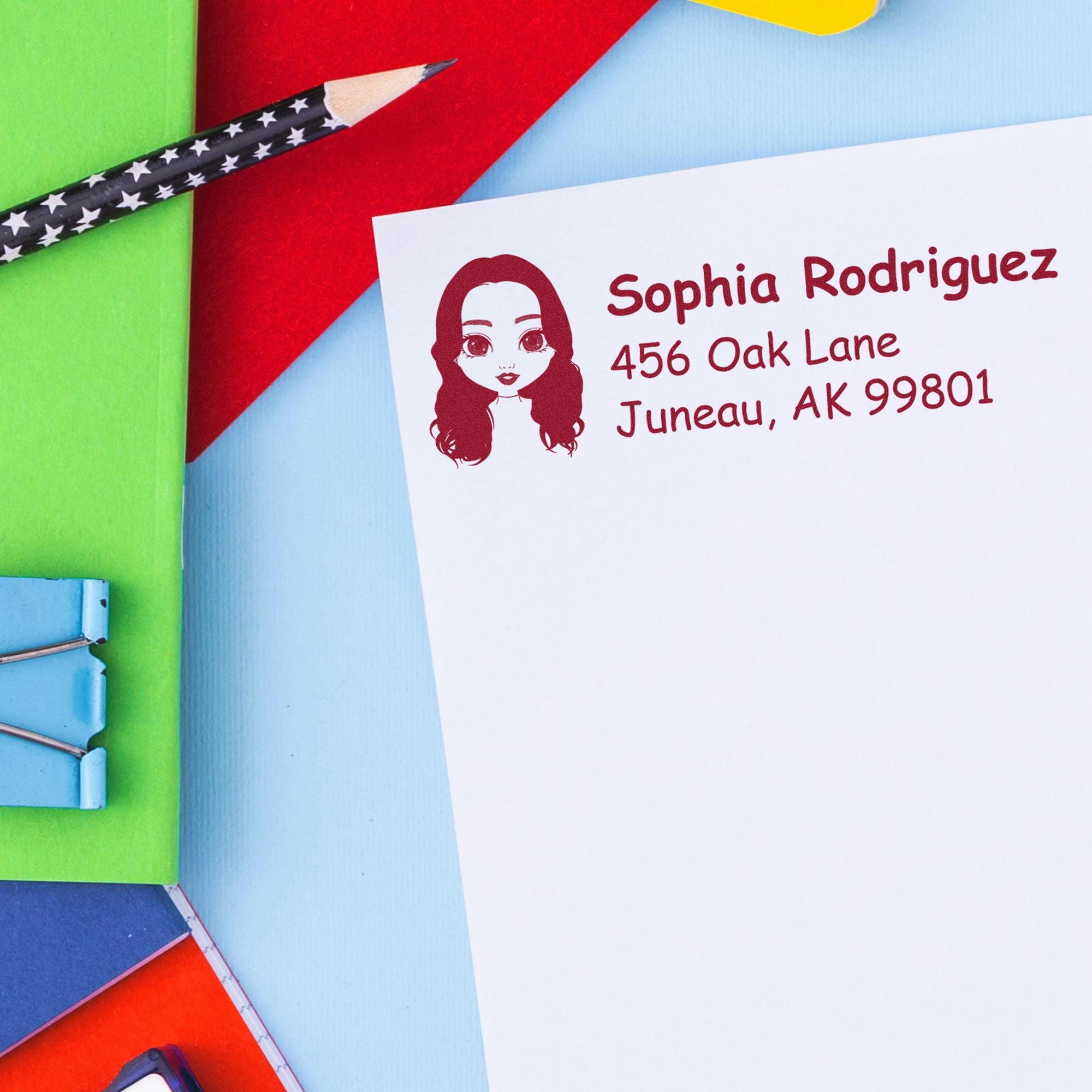 Burgundy custom address stamp and seal on white label, with pencil, against bright green, red and blue background.
