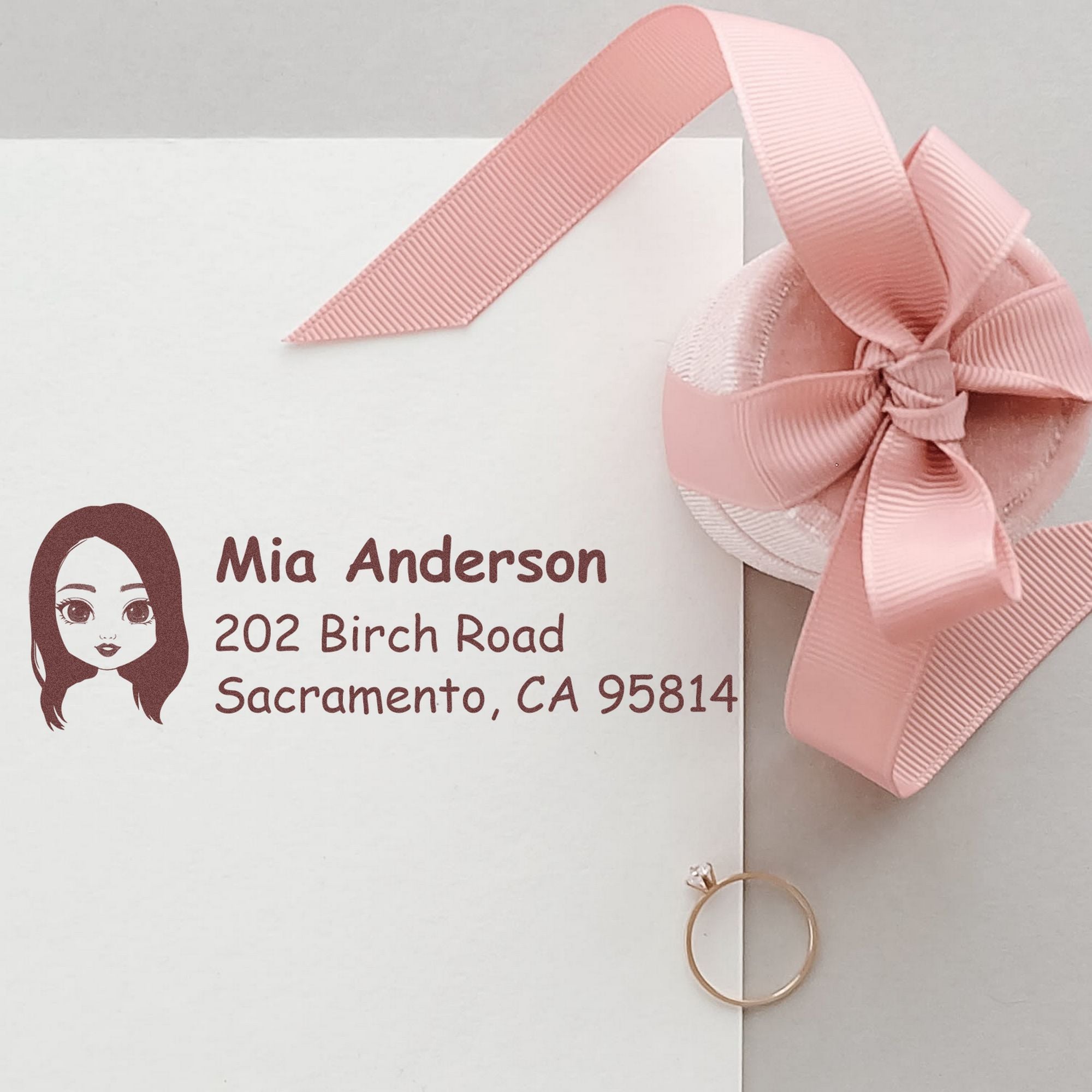 White envelope with pink ribbon seal and maroon custom address stamp for Mia Anderson, Sacramento, CA 95814