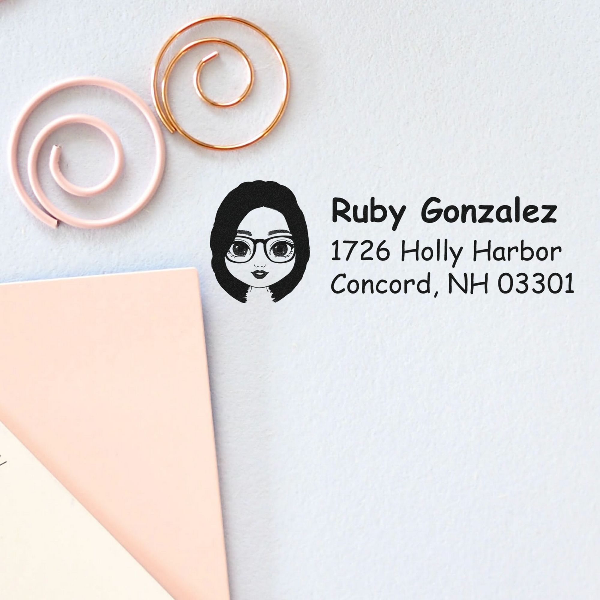 Custom address stamp and seal in black on white paper, with Ruby Gonzalez address, woman logo, and pink and gold spiral rings.