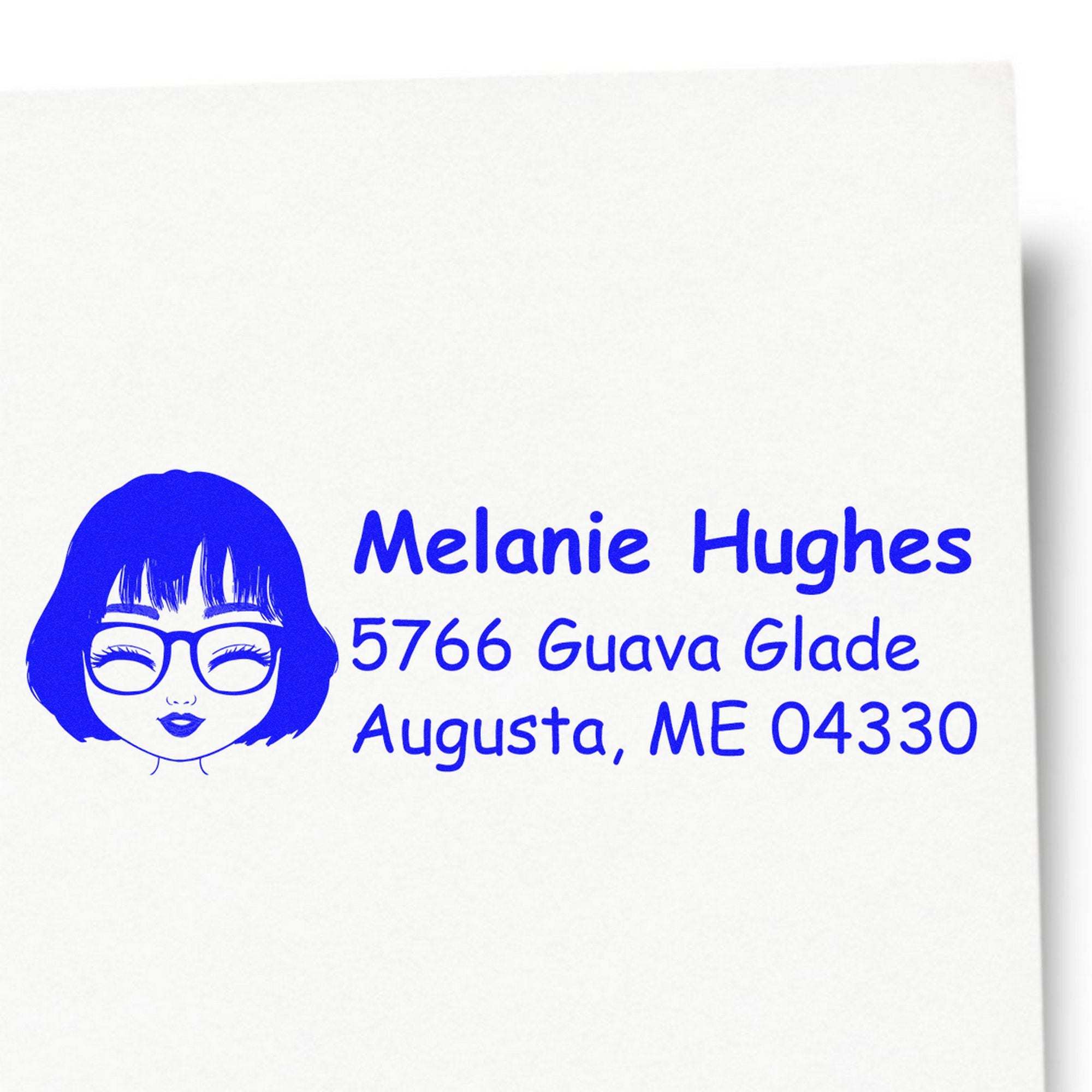 Blue custom address stamp with woman illustration, Melanie Hughes, 5766 Guava Glade, Augusta, ME 04330 on white paper.