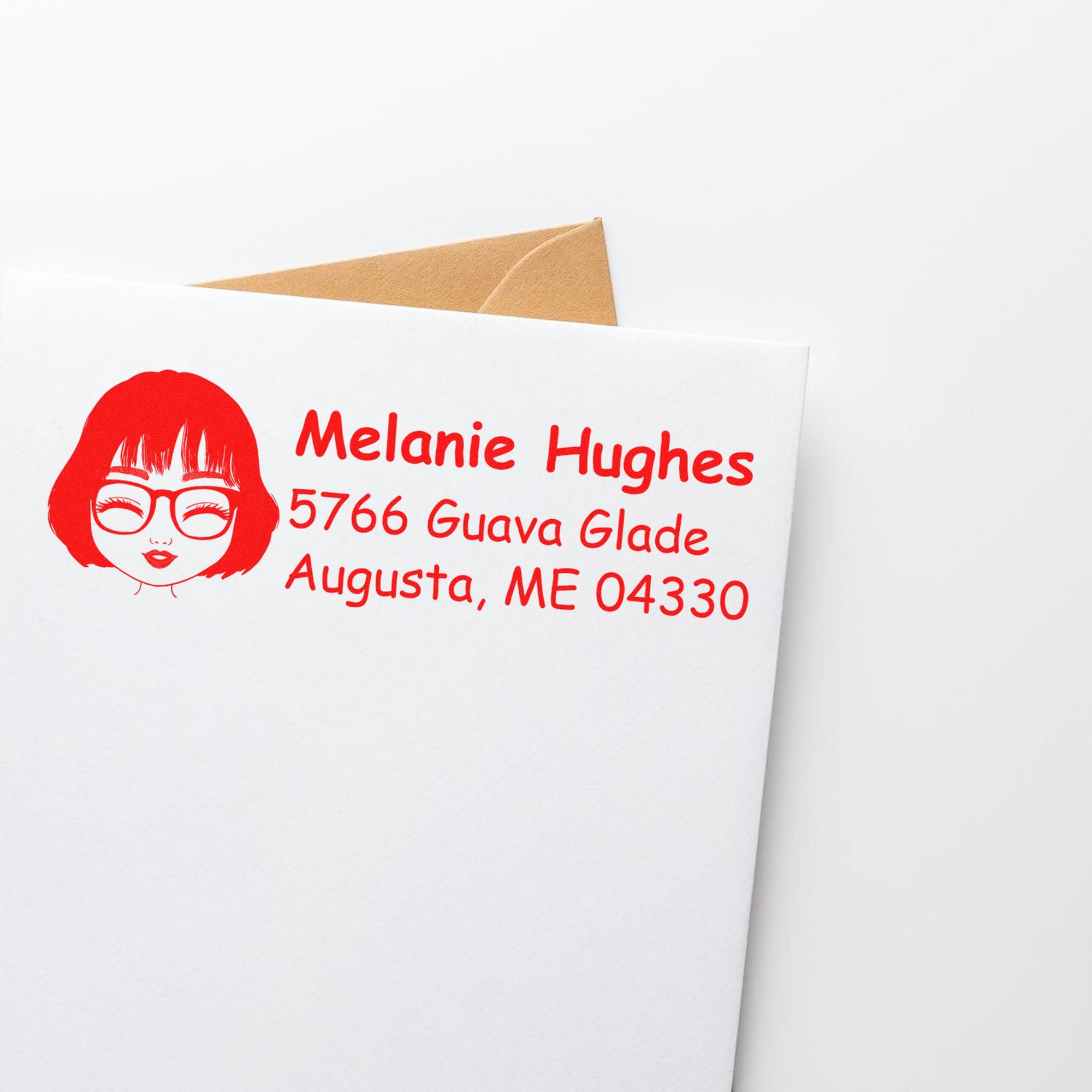 White envelope with tan insert and red custom return address stamp featuring a face icon and address text.