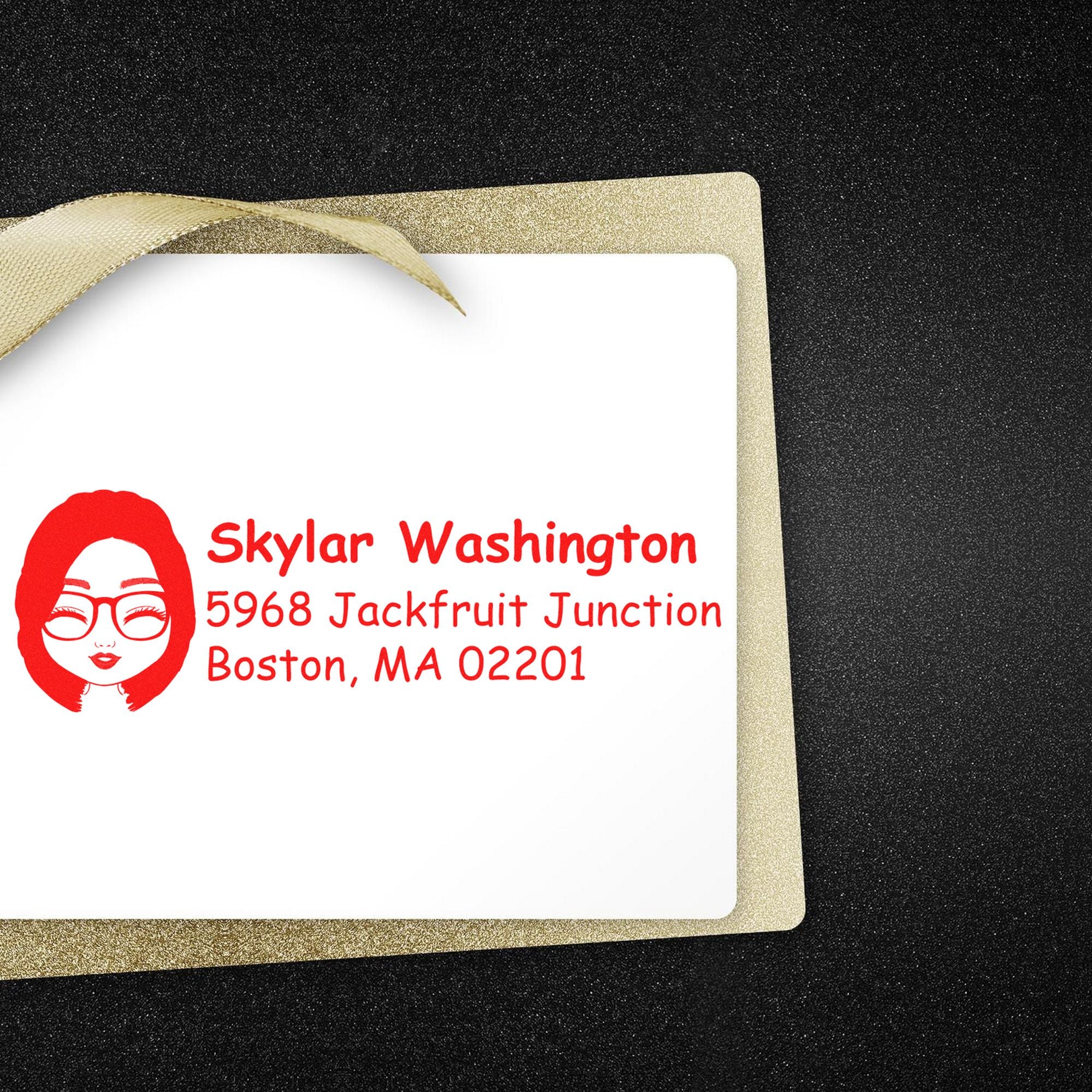 Gold glitter gift tag with white custom stamp seal, red face logo and address on black background with ribbon loop