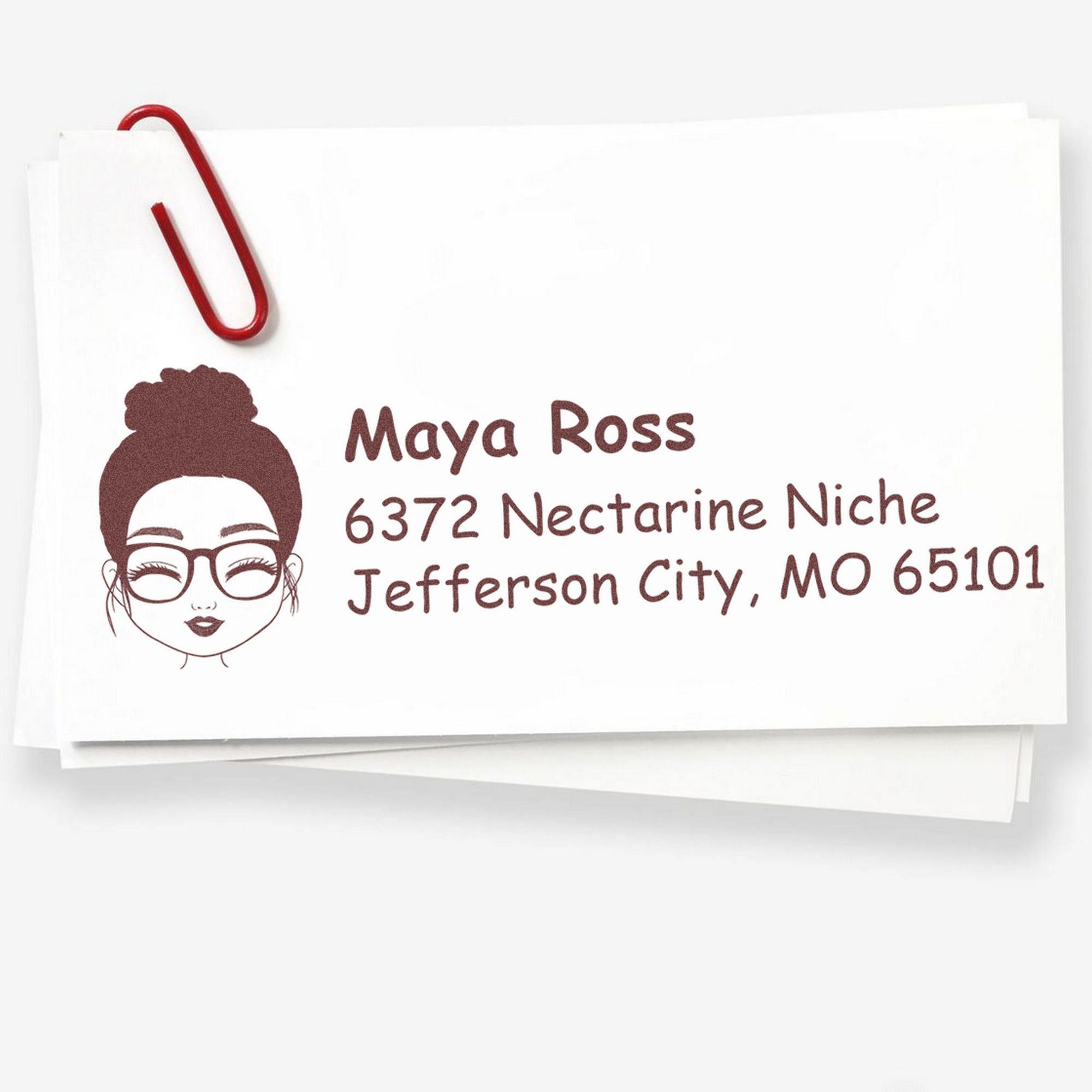 Custom burgundy address stamp and seal with illustrated woman, red paperclip, and name and address on white paper.
