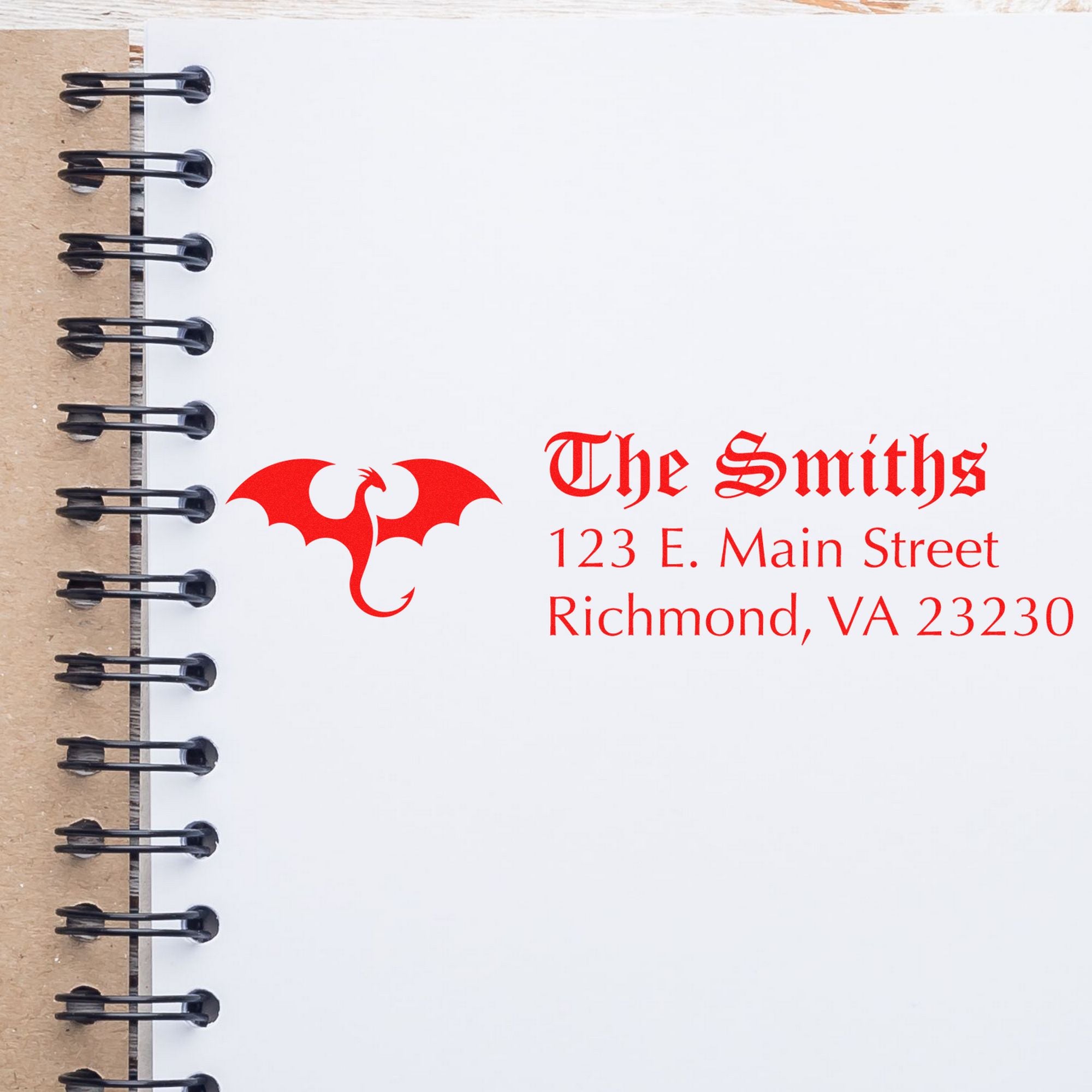 White notebook page with red dragon stamp seal and The Smiths address, spiral-bound on kraft cover.