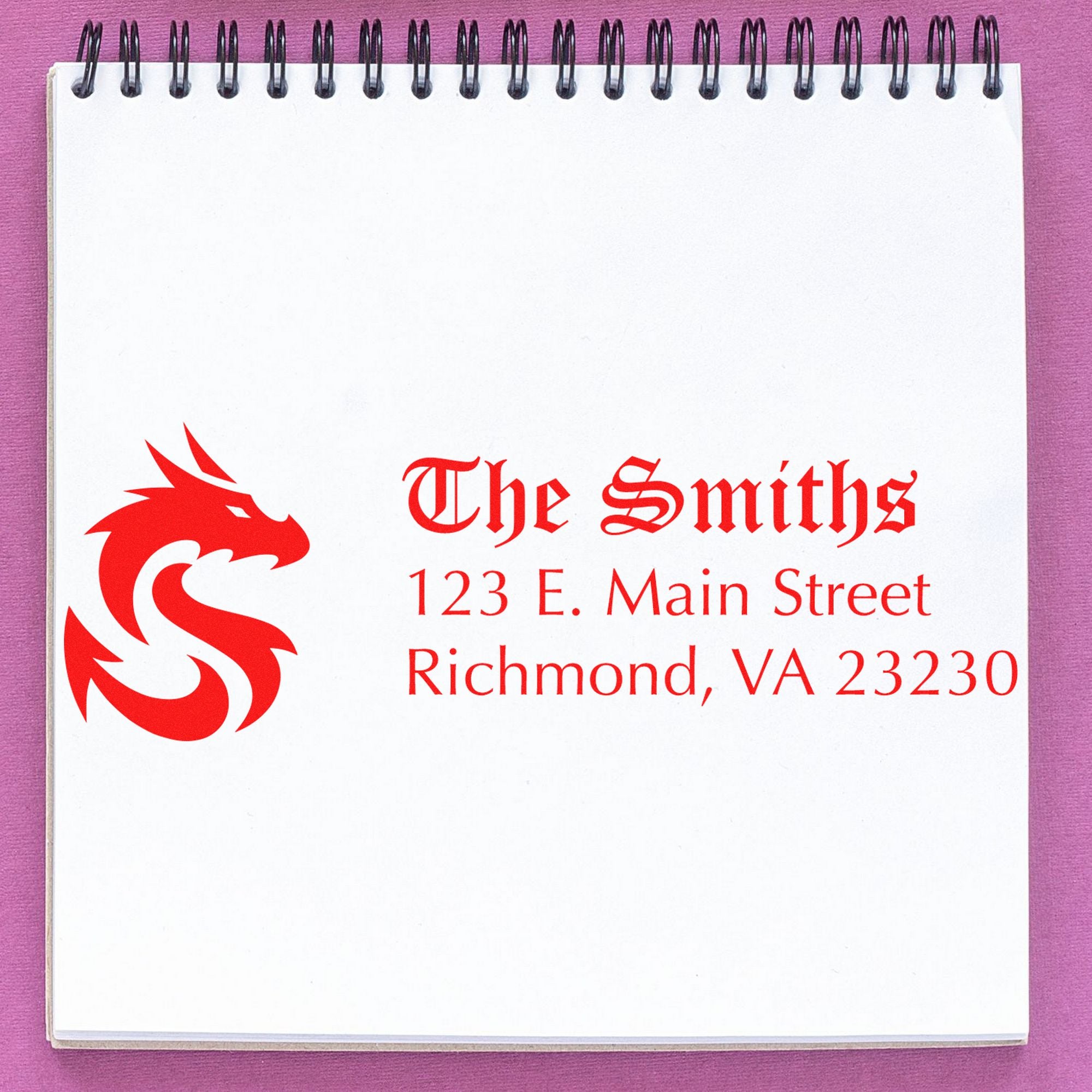 Red custom stamp and seal logo for The Smiths on white spiral notebook, with Richmond, VA address and dragon emblem on pink background.