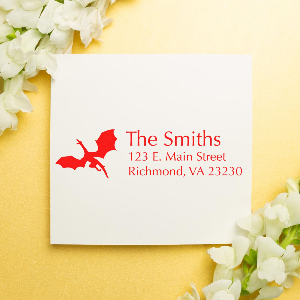 Red custom stamp and seal for The Smiths, with dragon logo and address on white card, against gold and white flowers.