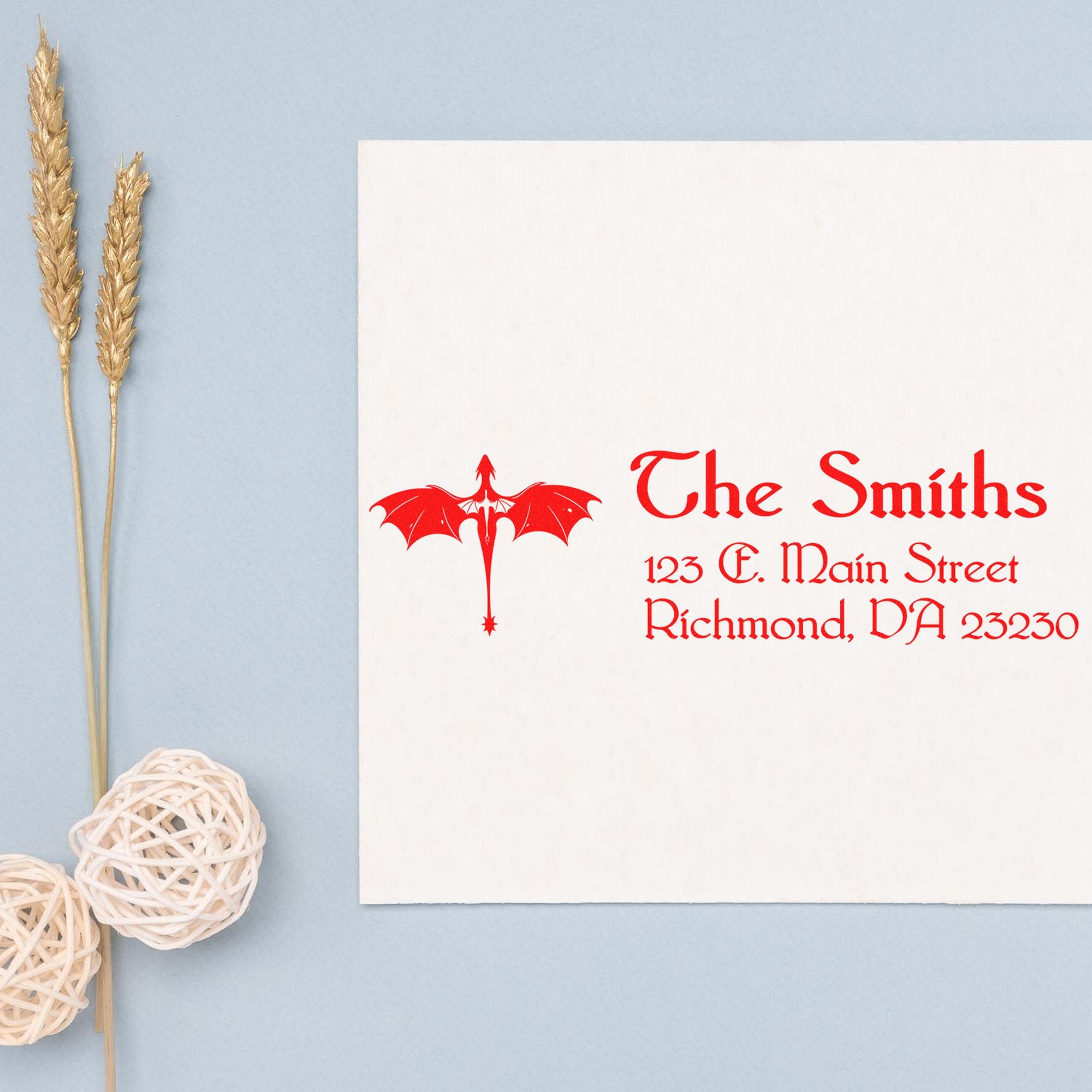 Custom red dragon stamp and seal on a white stationery card with red text, set against a pale blue background.