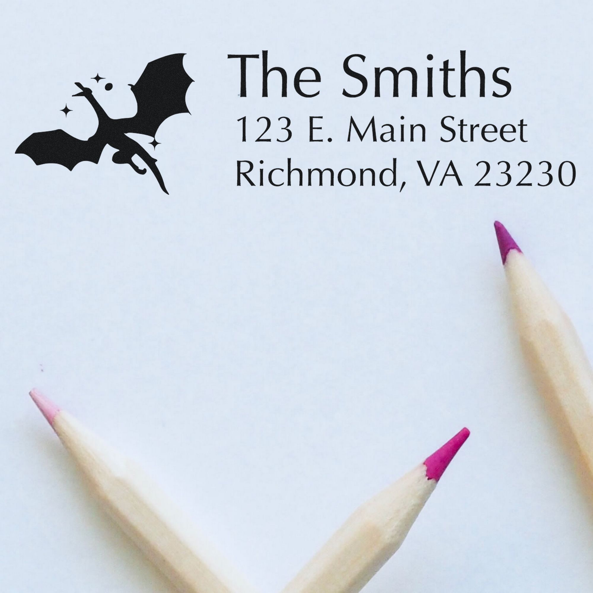 Custom black stamp and seal with bat logo, The Smiths address, on white paper with pink pencil tips.