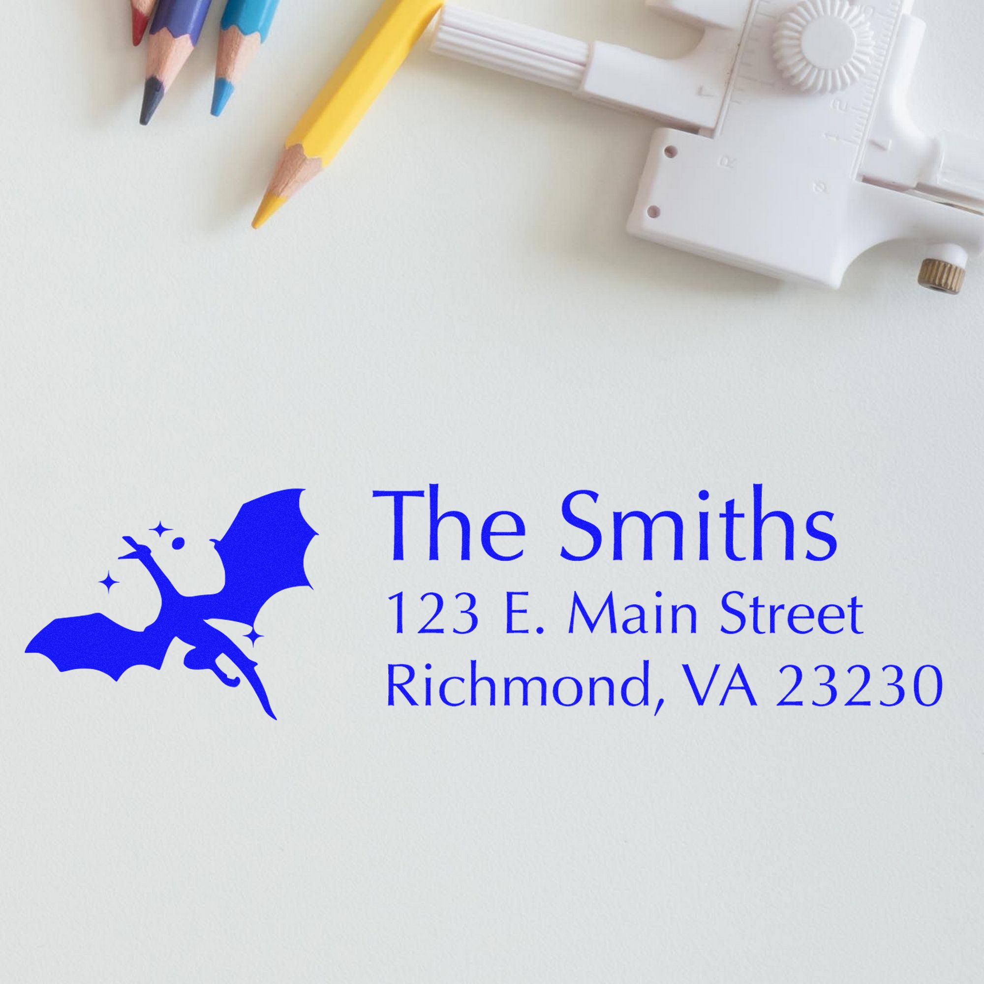 Custom blue bat address seal with white self-inking stamp and colored pencils on a white background