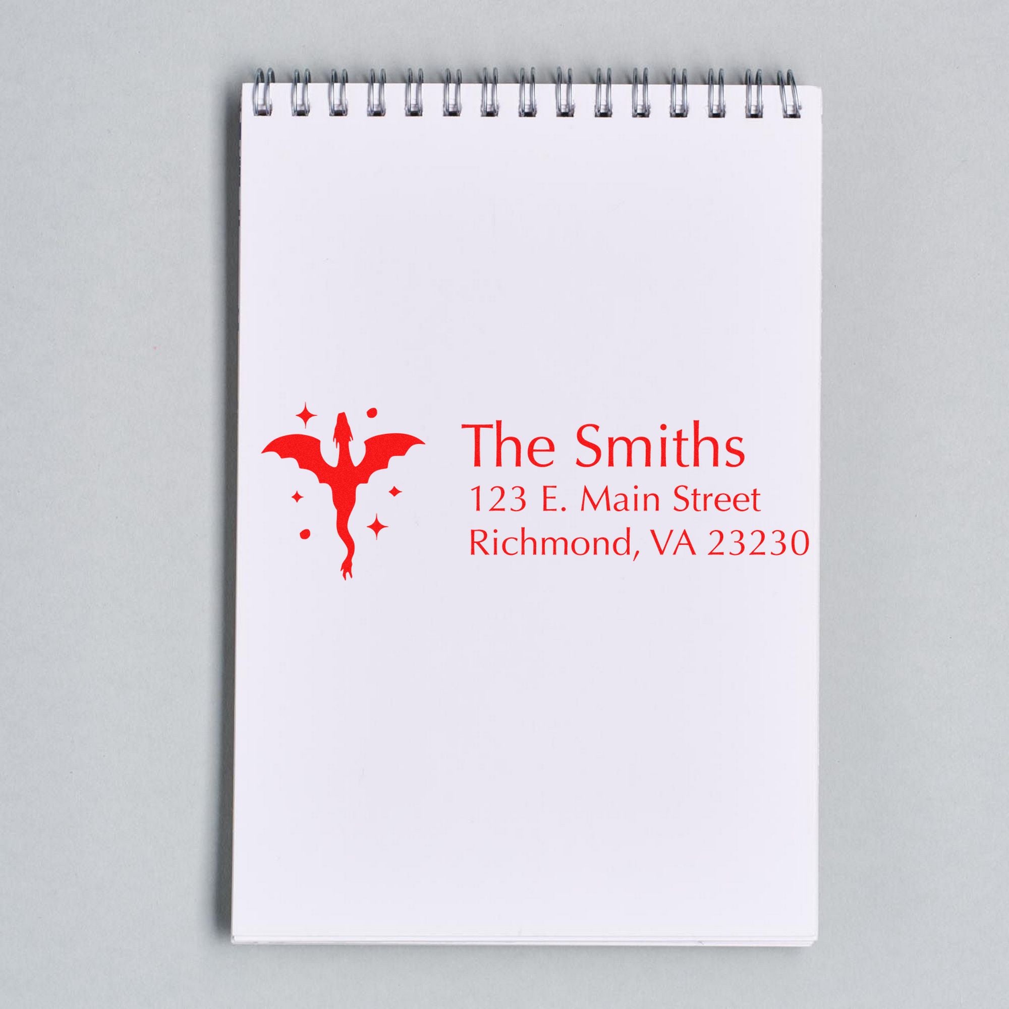 Red custom stamp and seal with dragon logo for The Smiths on a white spiral notepad.