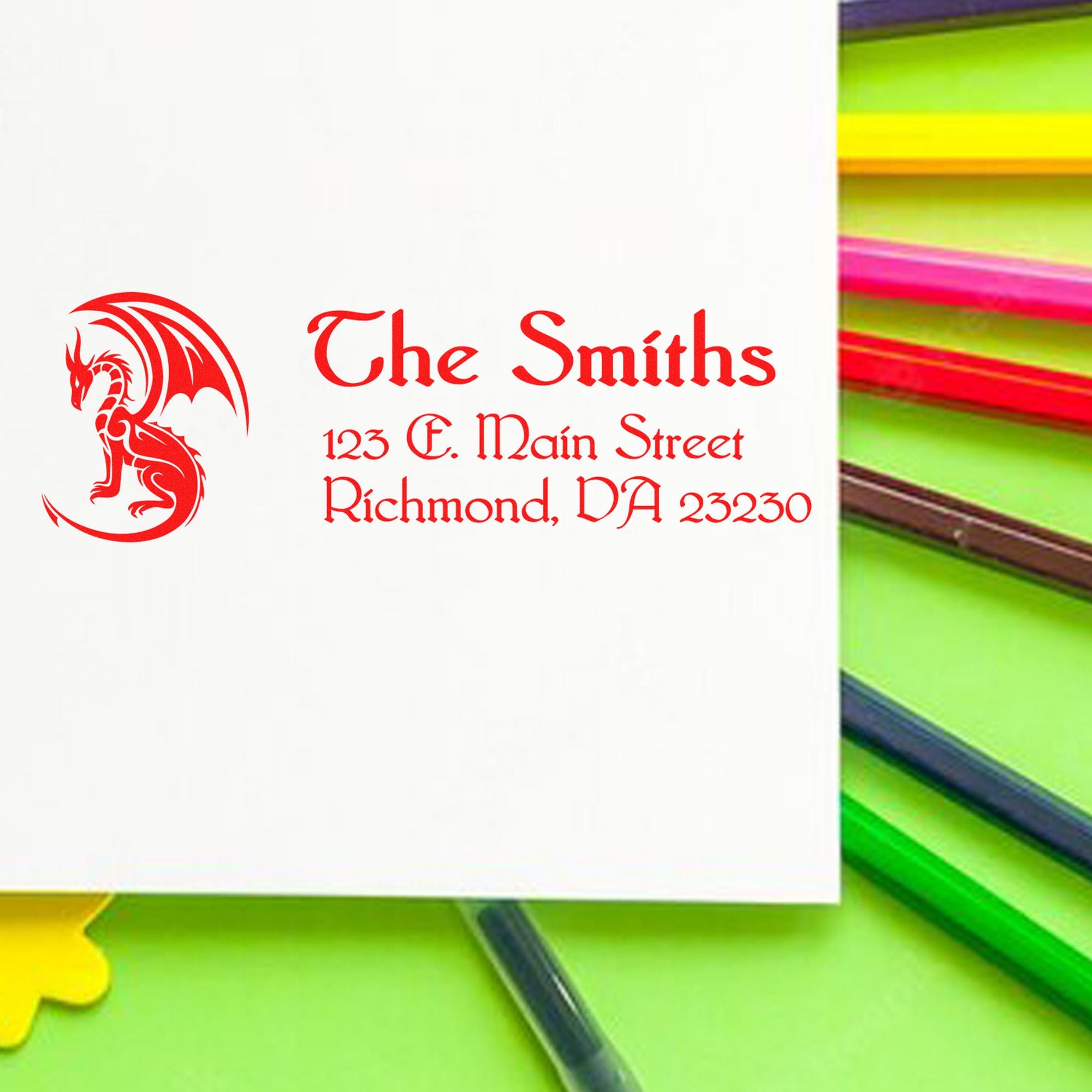 Red dragon custom address stamp with red text on white, beside bright green, pink and yellow stamp and seal handles.