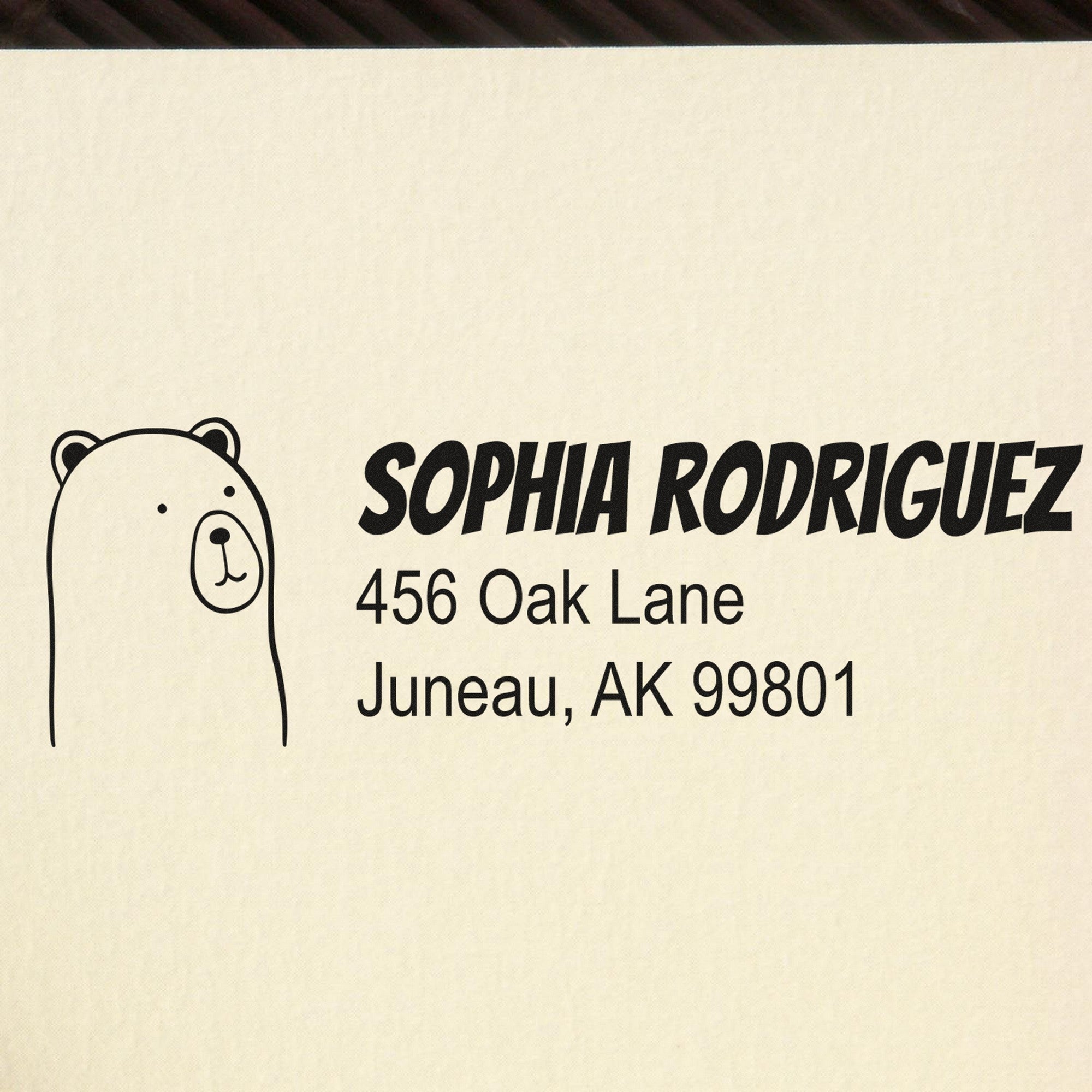 Image of a customizable address stamp featuring a wood handle cuddly polar bear design. The stamp displays the name "Sophia Rodriguez" with the address "456 Oak Lane, Juneau, AK 99801." Ideal for personalized return address rubber stamping.