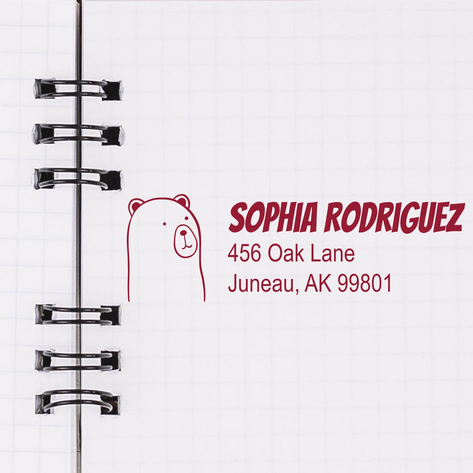 Cuddly Polar Bear Customize Mail Self-Inking Stamp featuring a bear illustration and personalized new address stamp with the name "Sophia Rodriguez" and address "456 Oak Lane, Juneau, AK 99801" on a spiral notebook page.