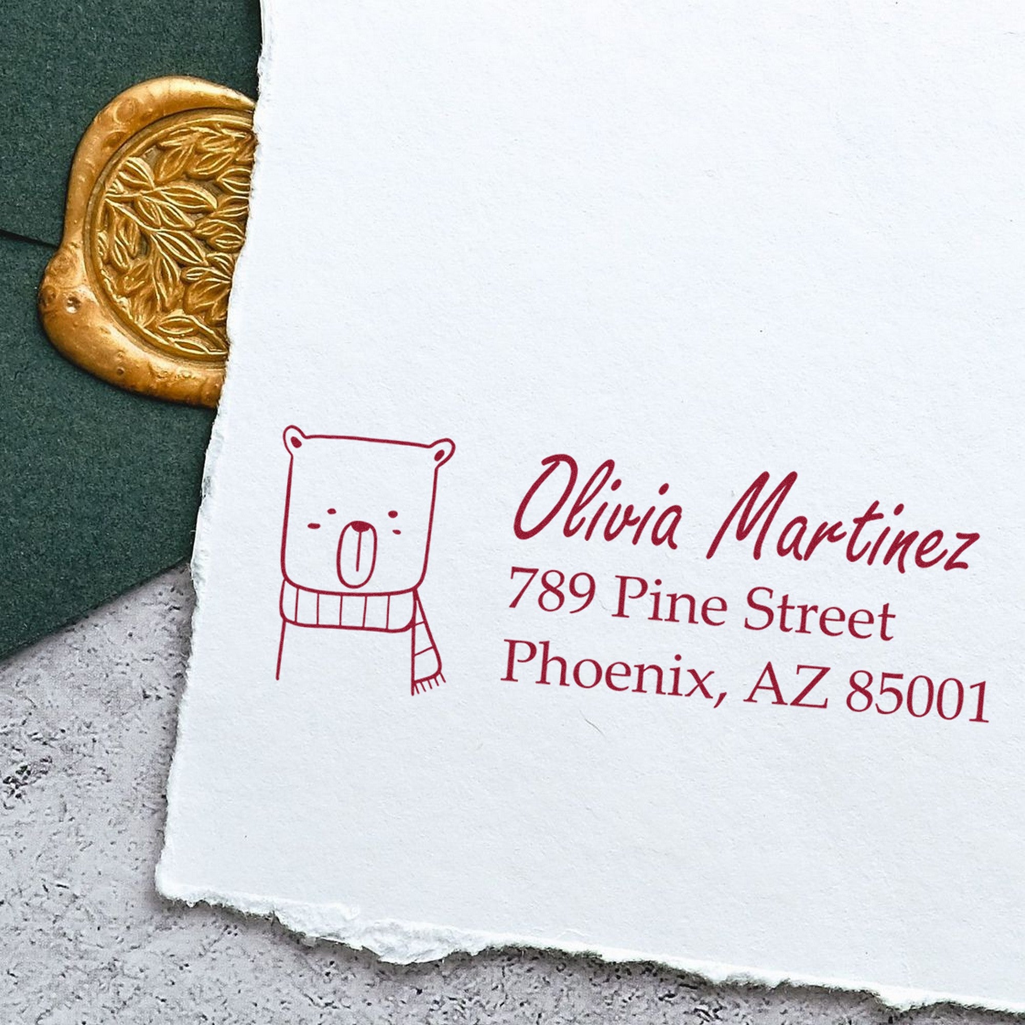 Wood Handle Snuggly Bear Personalized Name and Address Rubber Stamp on white paper with a bear illustration. Text reads "Olivia Martinez, 789 Pine Street, Phoenix, AZ 85001." Personalizable New Address Stamper next to a gold wax seal and green envelope.