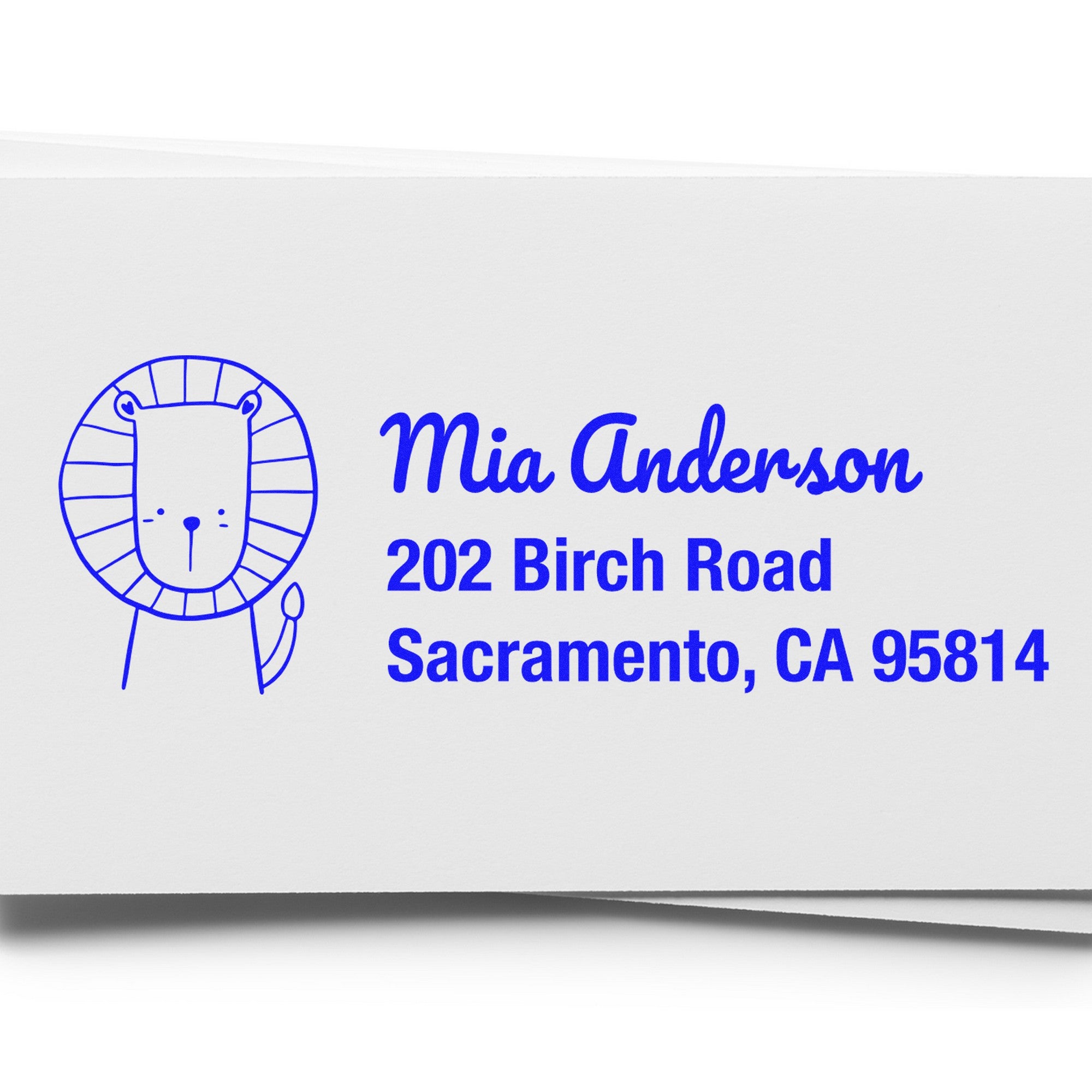Image of a personalized mail rubber stamp with a wood handle, featuring a cute lion illustration and the text "Mia Anderson, 202 Birch Road, Sacramento, CA 95814." The Little Roar design is ideal for a personalizable return mail stamper.