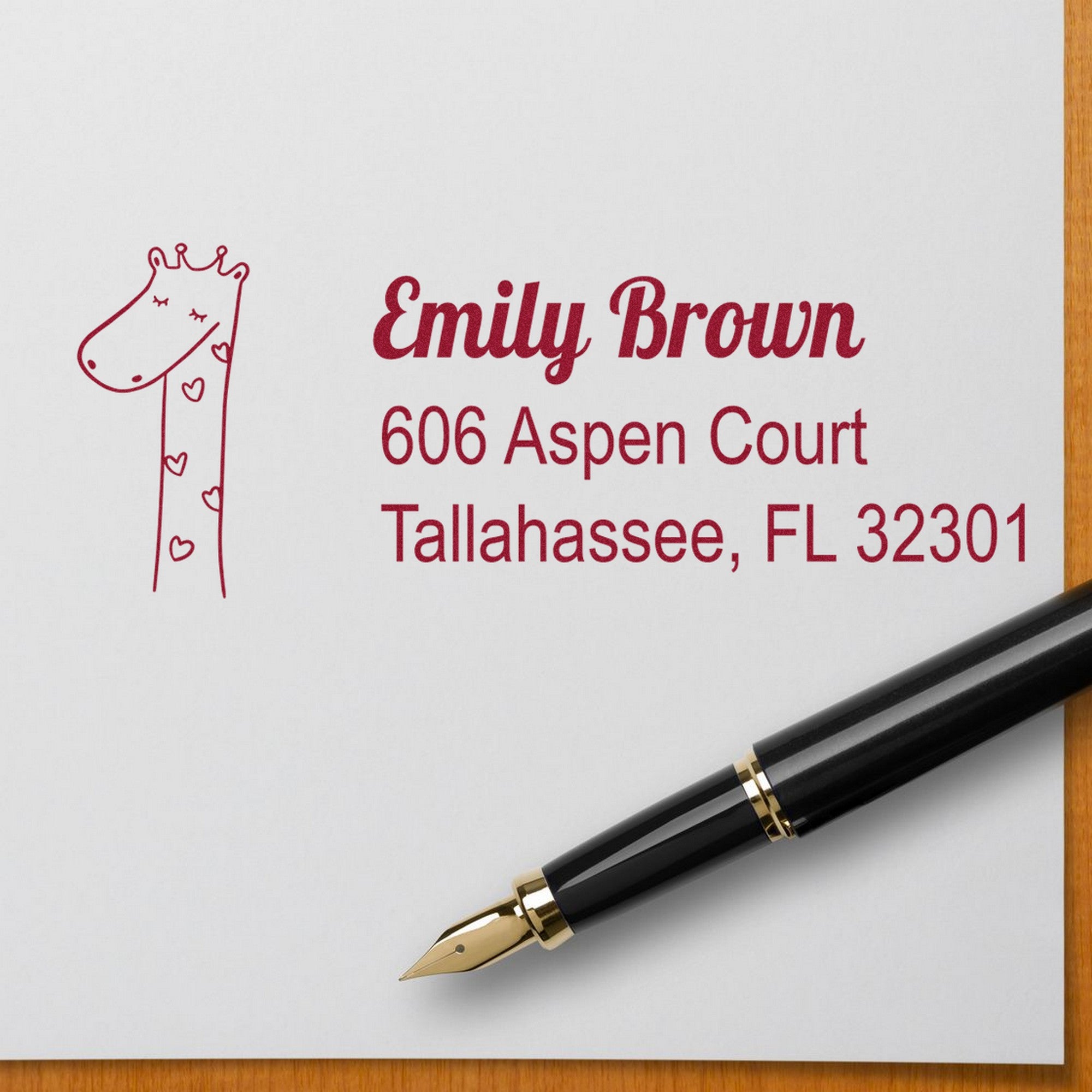 Lovely Giraffe Customize Address Label Self-Inking Stamp featuring a cute giraffe design and personalized new address stamp with the name Emily Brown, 606 Aspen Court, Tallahassee, FL 32301, shown on white paper with a black fountain pen.