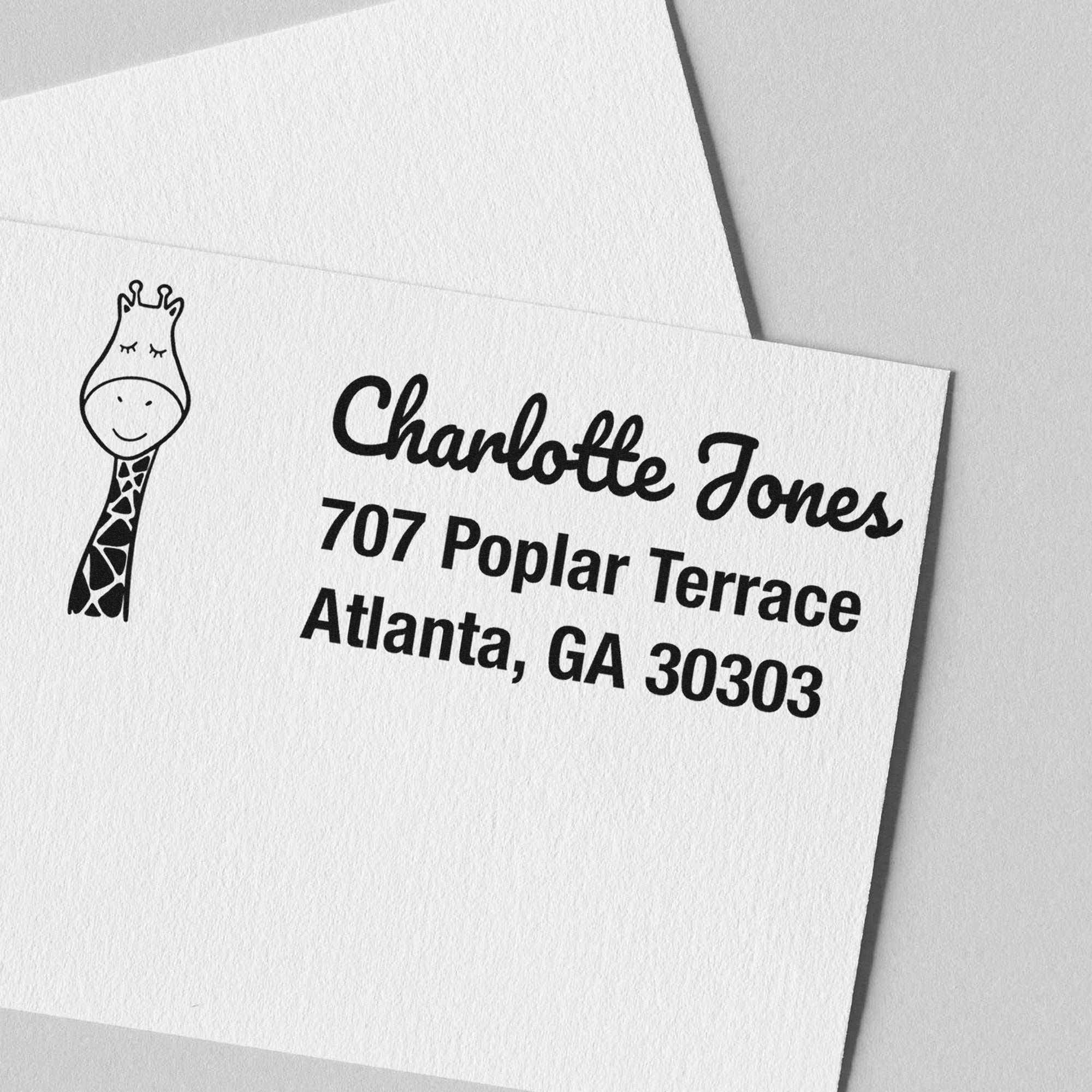 PSI Jolly Giraffe Handmade Mailing Pre-Inked Stamp on a card with "Charlotte Jones, 707 Poplar Terrace, Atlanta, GA 30303" text. The Customized New Address Stamper features a cute giraffe illustration on white paper.