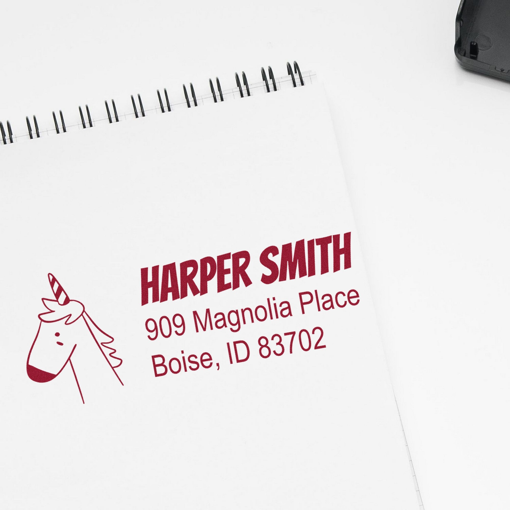 PSI Whimsical Unicorn Handmade Home Address Pre-Inked Stamp on paper with "Harper Smith, 909 Magnolia Place, Boise, ID 83702" in red. Personalizable Home Stamp design features a cute unicorn illustration.