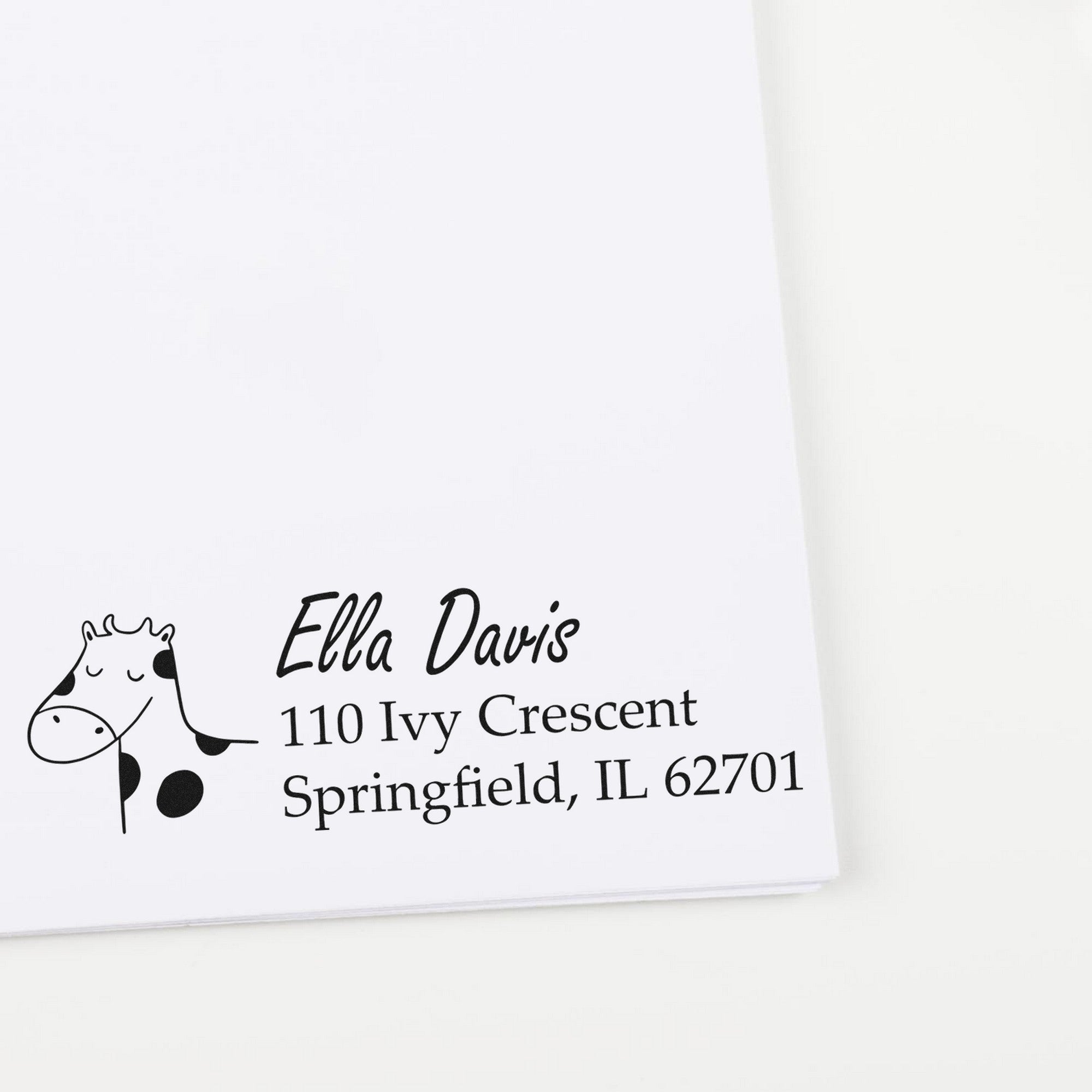 A custom new address stamp featuring a wood handle giraffe grins design. The stamp displays the name Ella Davis with the address 110 Ivy Crescent, Springfield, IL 62701 on white paper.