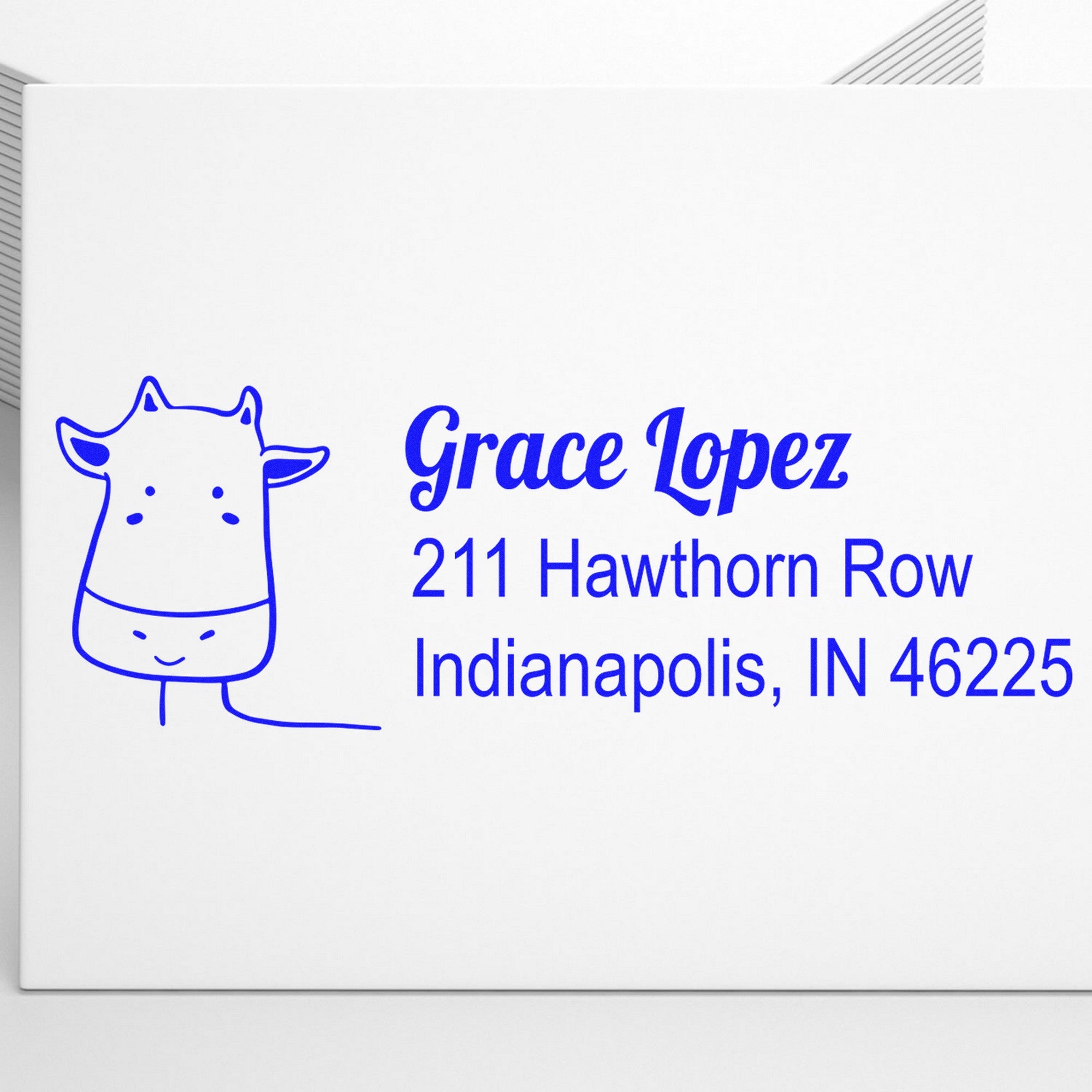 Wood Handle Cow Cuddles Custom Return Address Rubber Stamp on an envelope, featuring a cute cow illustration and customizable address stamper with the name "Grace Lopez" and address "211 Hawthorn Row, Indianapolis, IN 46225" in blue ink.
