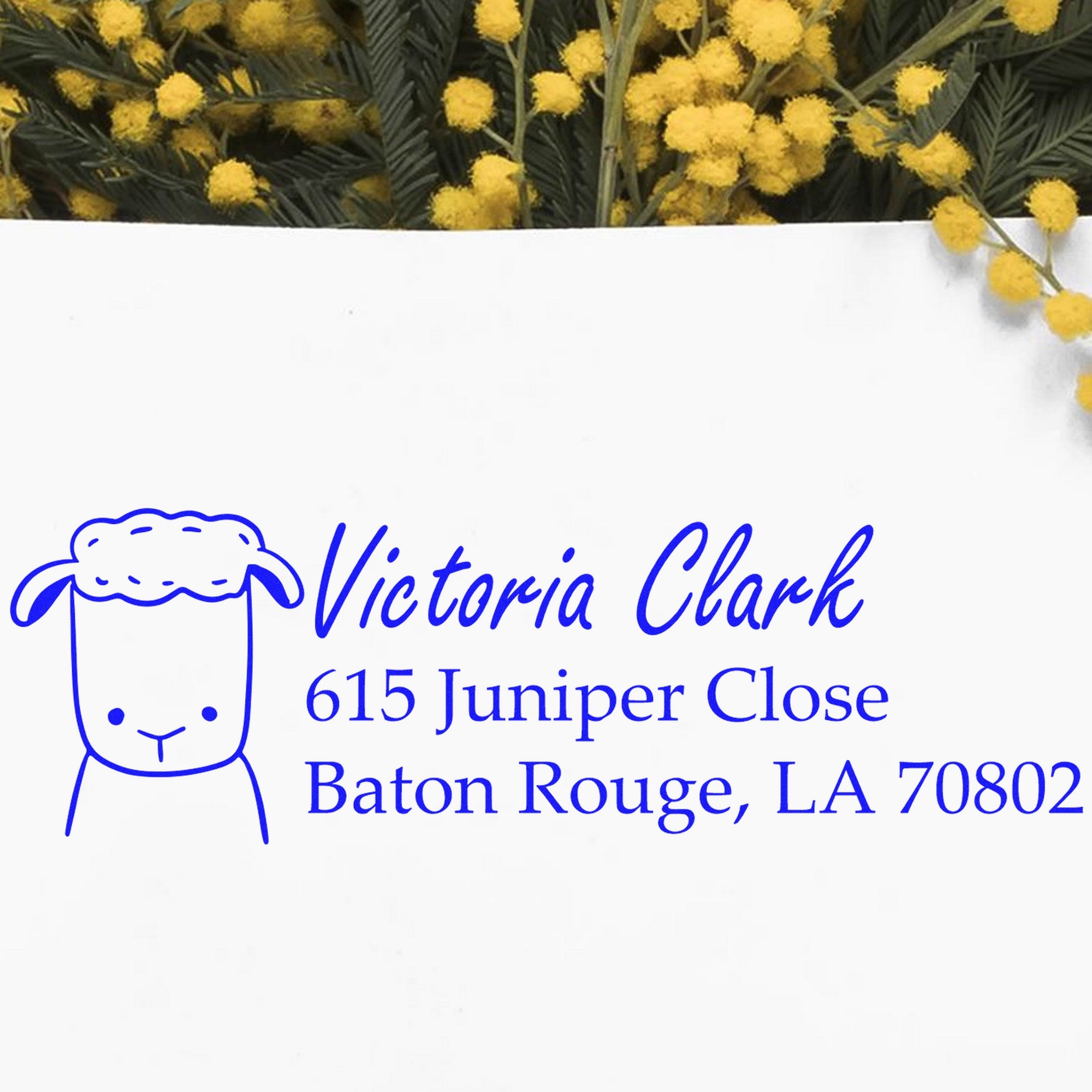 Wood Handle Fluffy Sheep Custom Home Address Rubber Stamp on white paper with blue ink, featuring a cute sheep design and personalized address. Background includes yellow flowers. Ideal for a Customized Home Stamper.