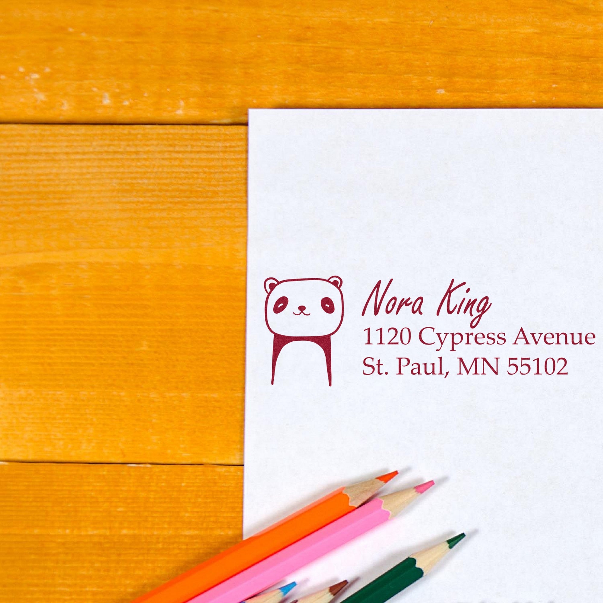 Wood handle playful panda custom home address for envelopes rubber stamp on white paper, featuring a cute panda design. Customizable new address stamper shown with colored pencils on a wooden surface.