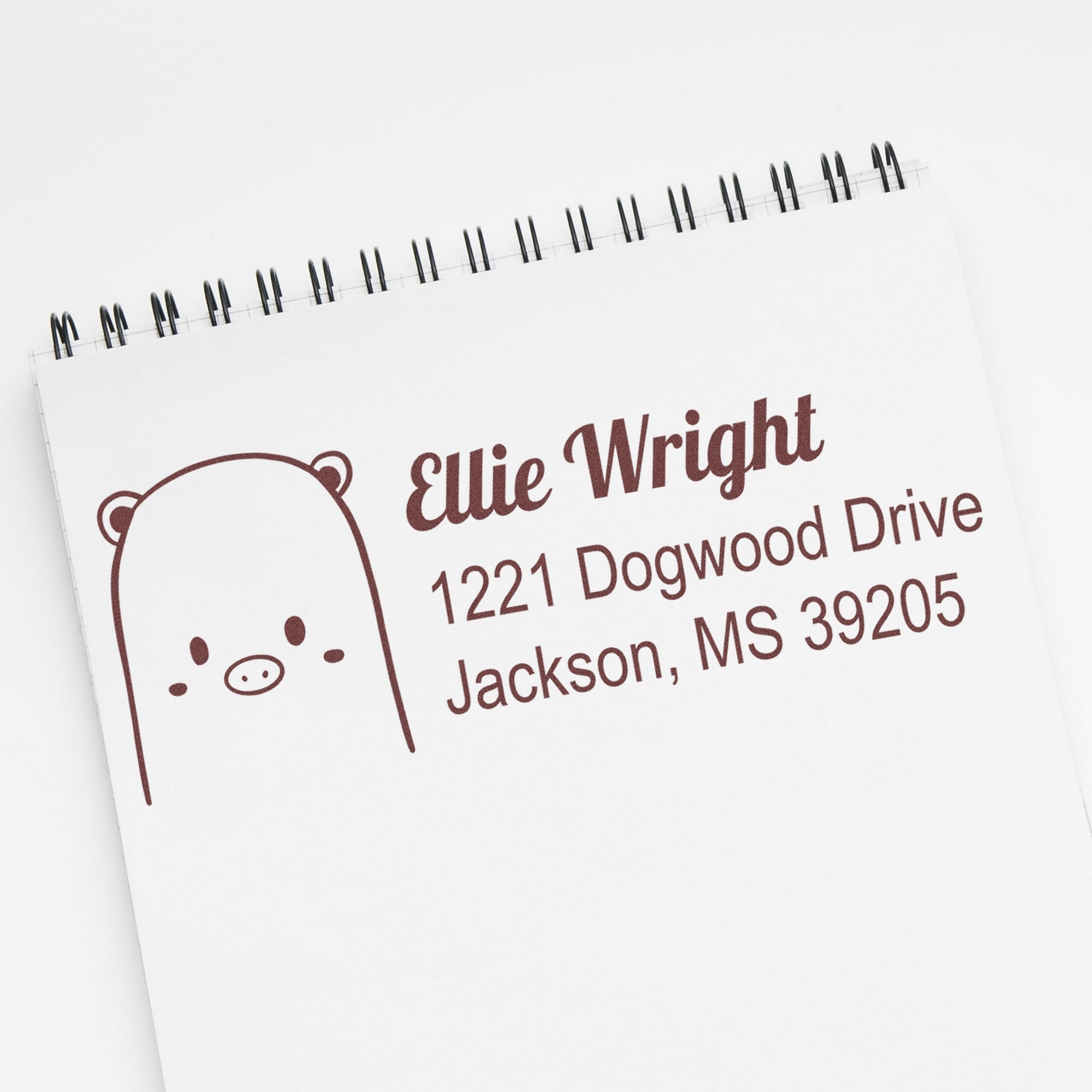 Wood handle rubber stamp with a beautiful bear design, used as a personalized address stamper. The custom address label displays "Ellie Wright, 1221 Dogwood Drive, Jackson, MS 39205" on a notepad.