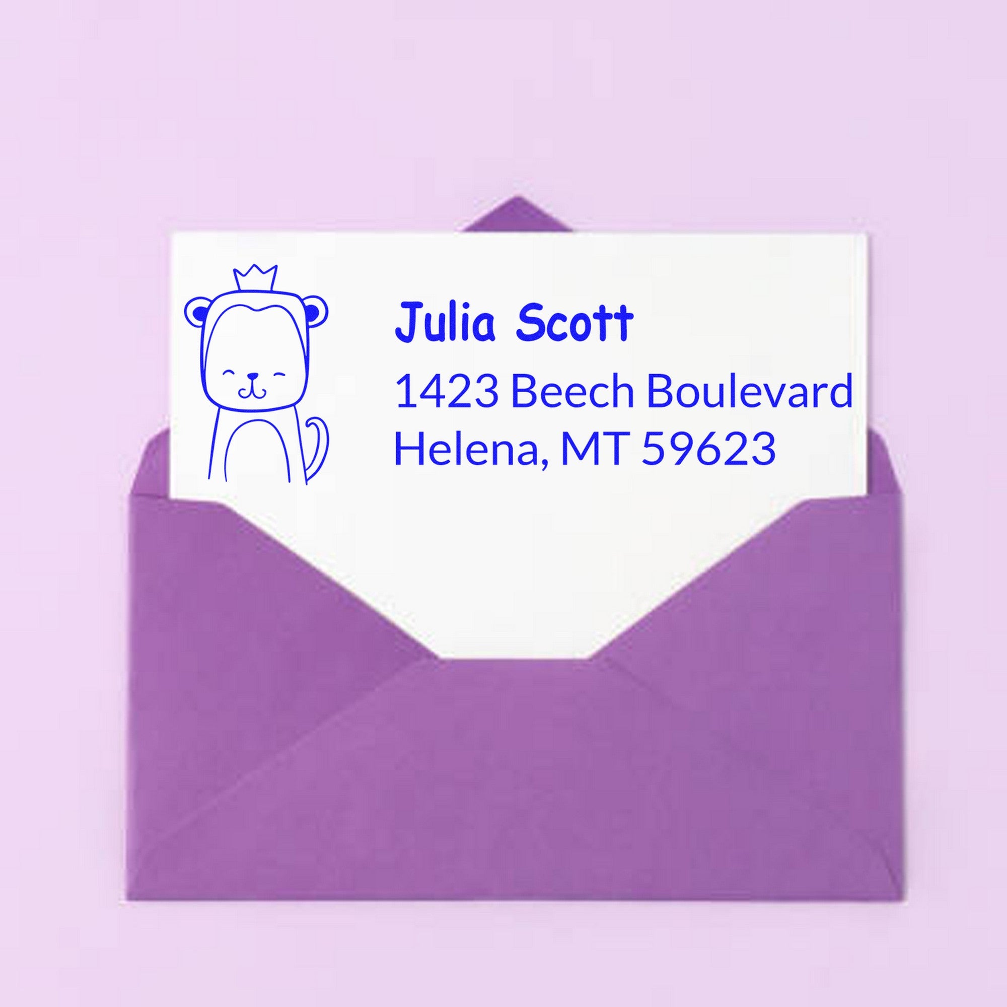Purple envelope with a card featuring a blue mischievous monkey design and text. The card displays a customized address stamp with the name Julia Scott, 1423 Beech Boulevard, Helena, MT 59623. Wood handle mischievous monkey customized return address rubber stamp.