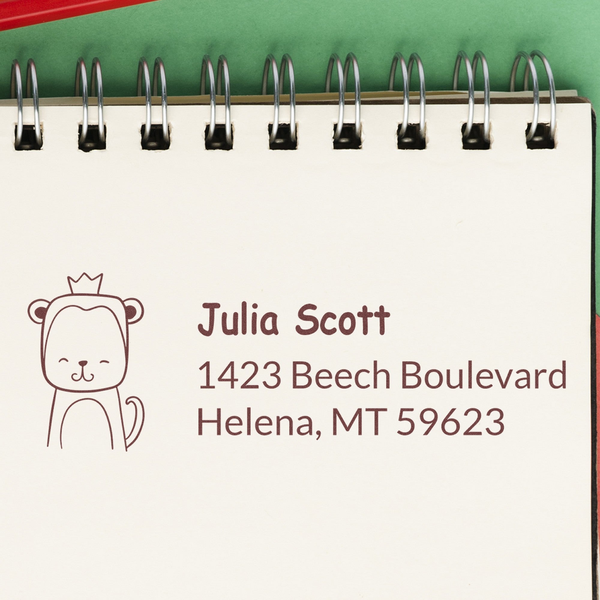 Wood Handle Mischievous Monkey Customized Return Address Rubber Stamp on a notepad, featuring a cute monkey design with a crown. The Customized Address Stamper displays the name Julia Scott and an address in Helena, MT.