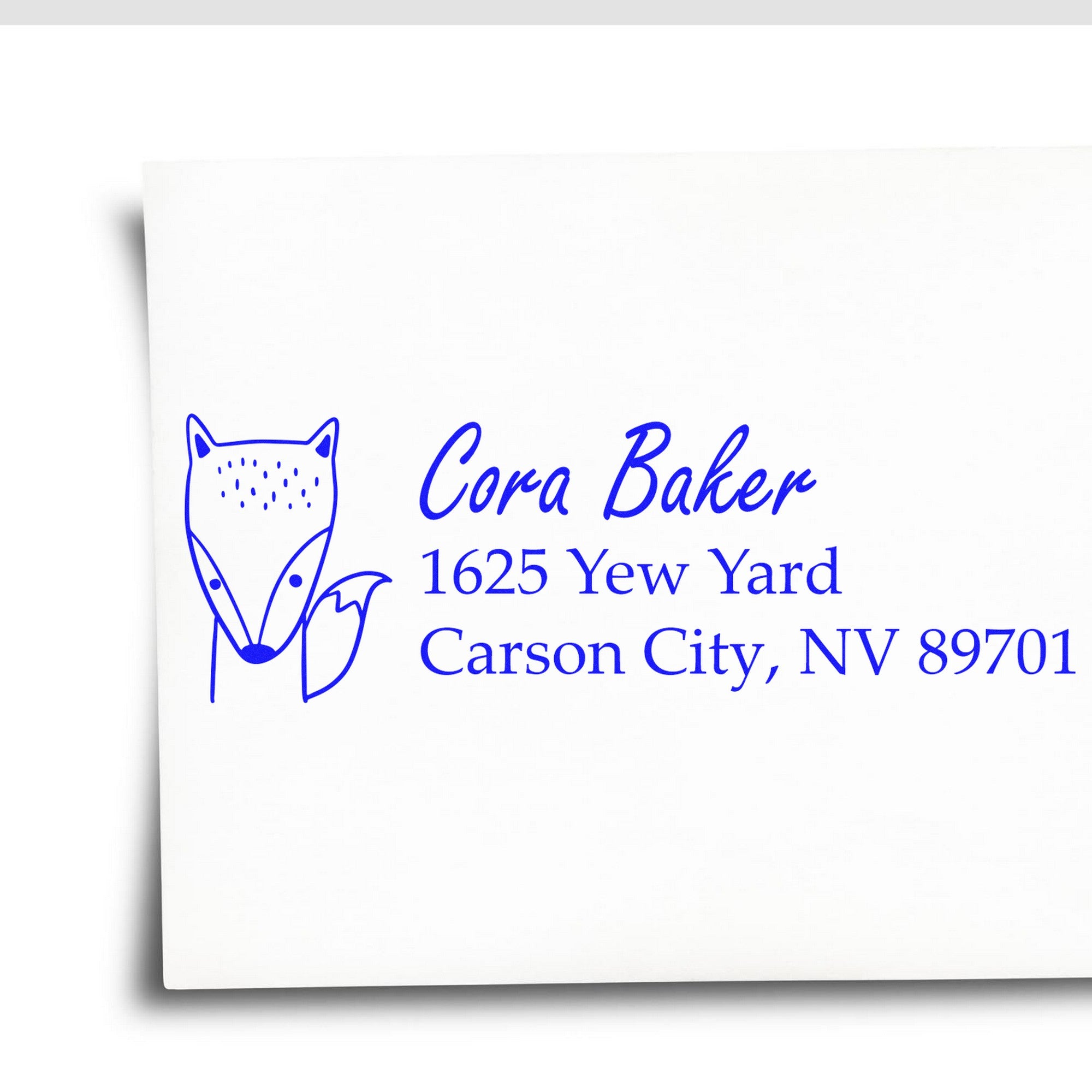 Image of an envelope stamped with a blue fox design and personalized address. The stamp features a wood handle and is labeled as a "Fast Fox Customized Mailing Rubber Stamp" and "Personalizable New Address Stamper."