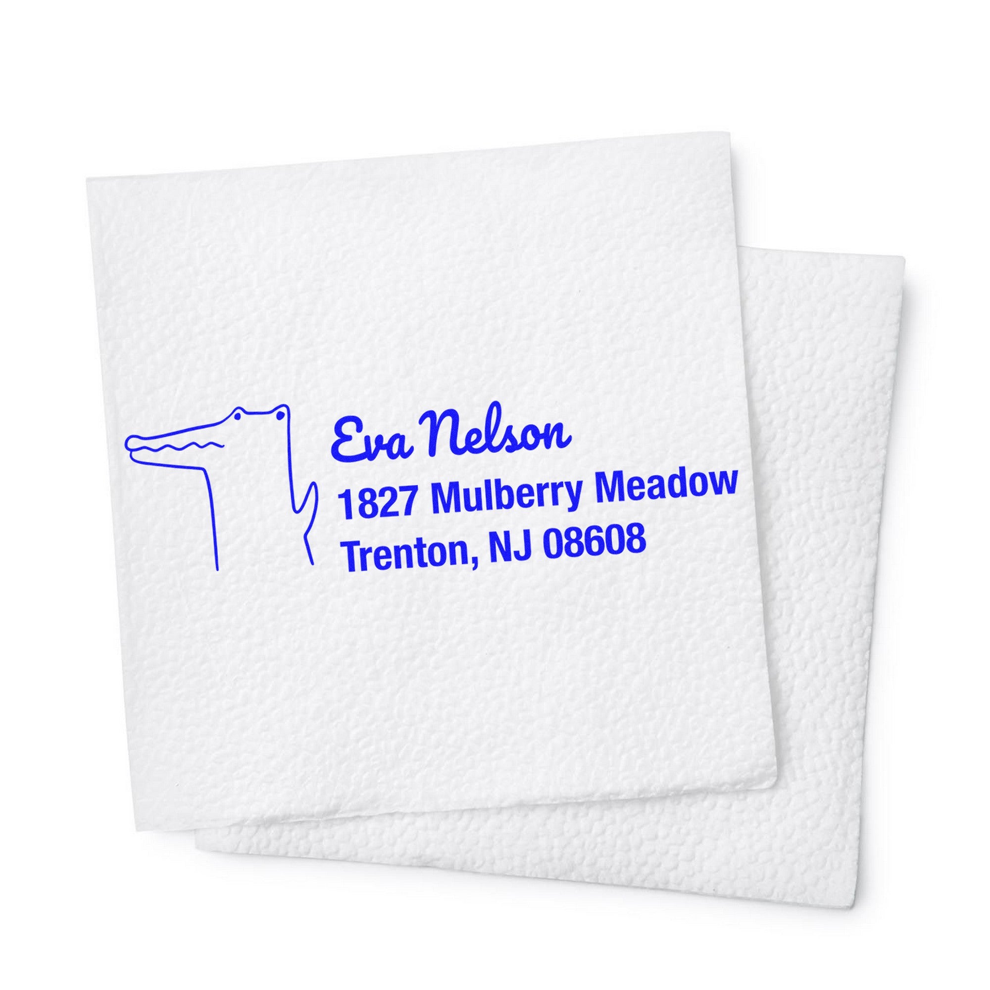 Charming Crocodile Personalized Mail Address Self-Inking Stamp displayed on a white napkin. The design features a crocodile illustration with the text "Eva Nelson, 1827 Mulberry Meadow, Trenton, NJ 08608," showcasing a Personalized Home Stamp.