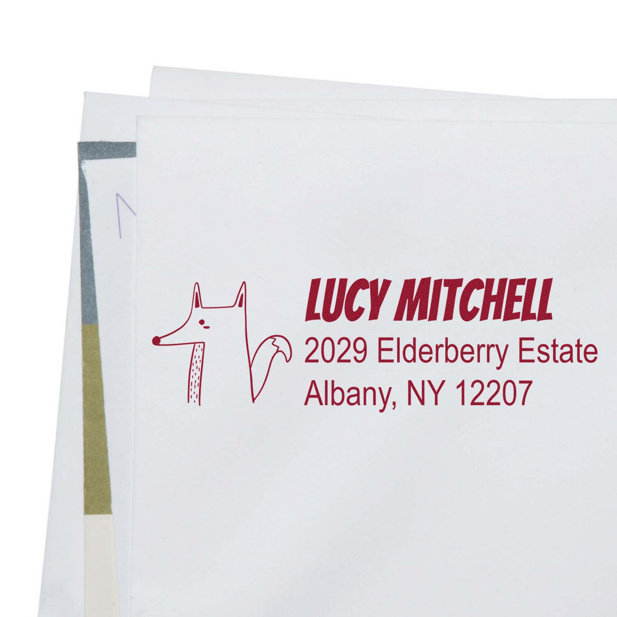 Envelope with a red Finicky Fox Personalized Home Address For Envelopes Self-Inking Stamp, featuring a fox illustration and custom return mail stamper details: "Lucy Mitchell, 2029 Elderberry Estate, Albany, NY 12207."