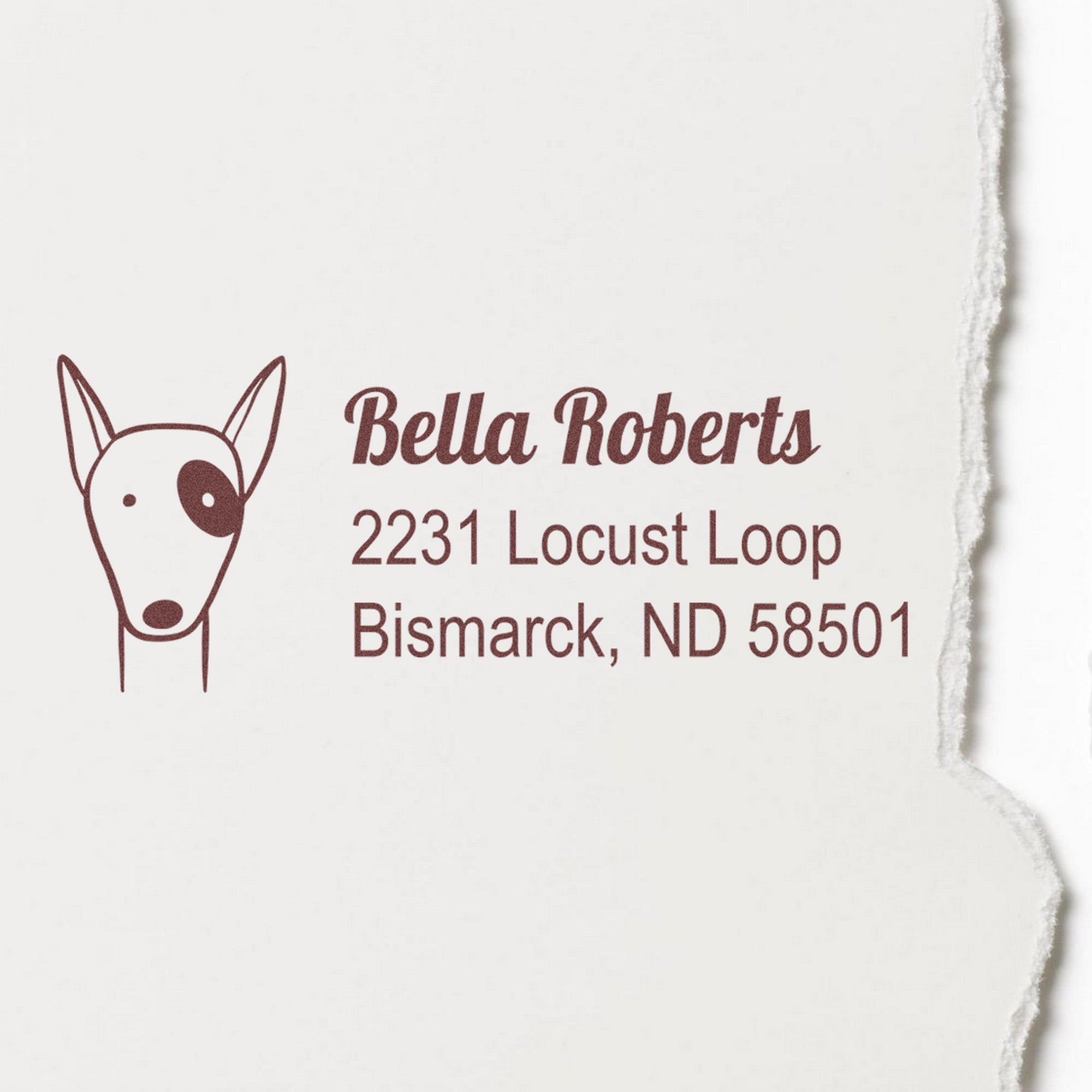 PSI Perky Pooch Customizable Mailing Pre-Inked Stamp featuring a dog illustration and personalized home stamp with the name Bella Roberts and address 2231 Locust Loop, Bismarck, ND 58501 on a torn paper background.